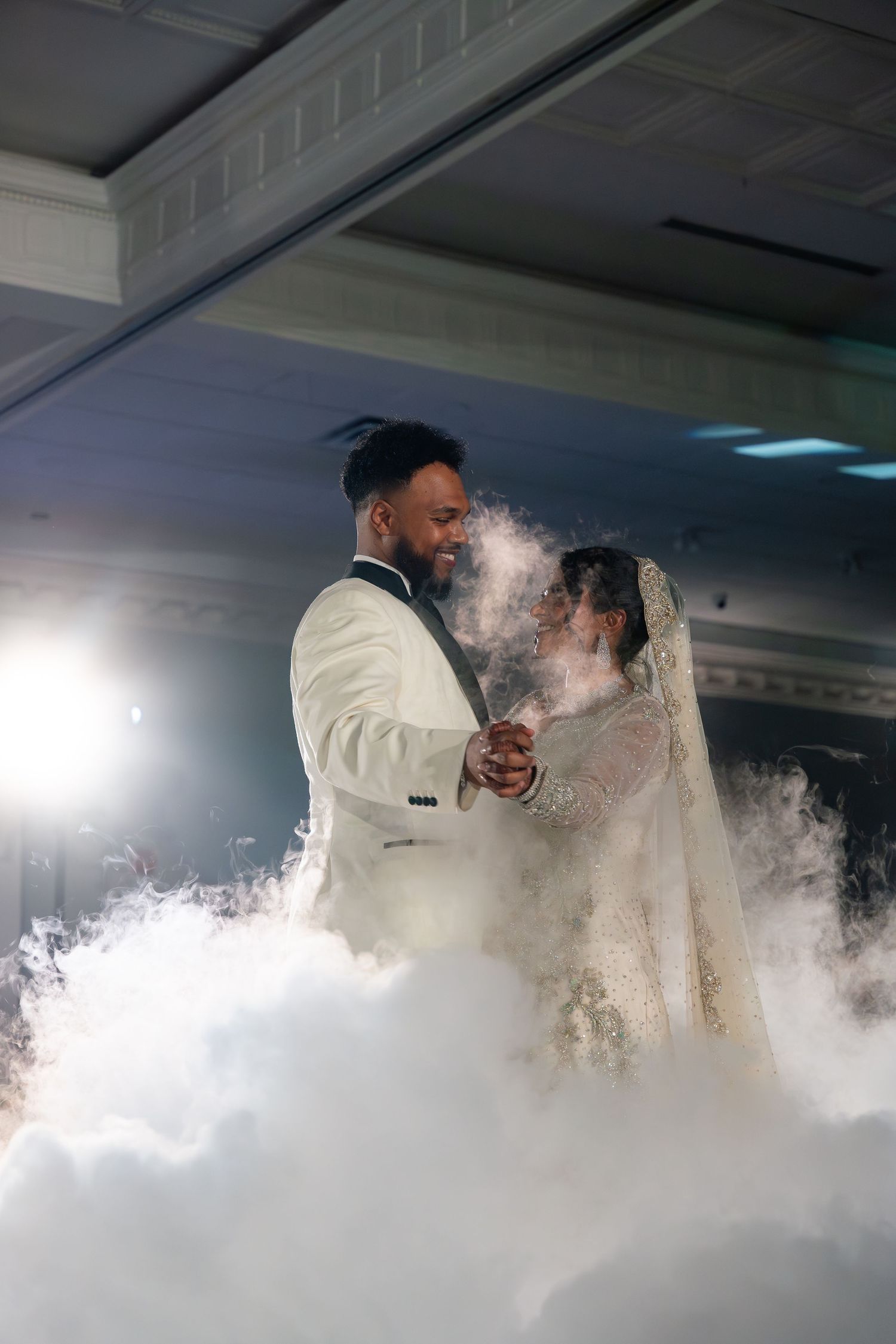 Newlyweds share their first dance surrounded by ethereal fog effects on the dance floor at their wedding reception.