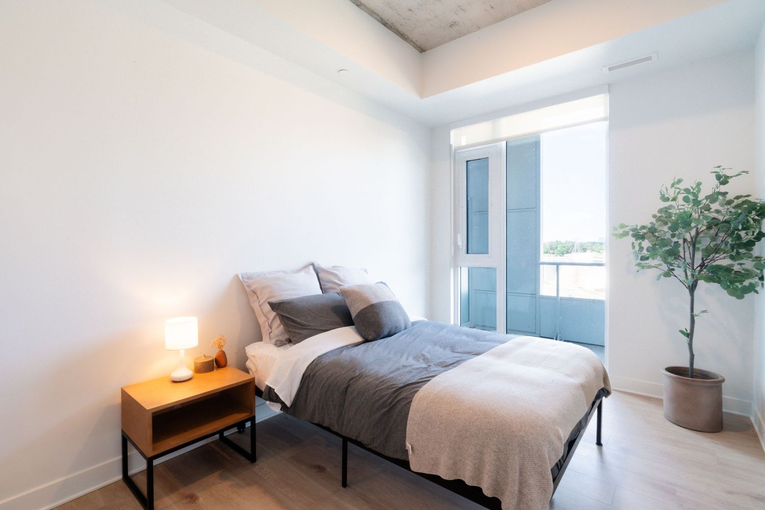 Clean and bright bedroom interior with modern furnishings and large windows.