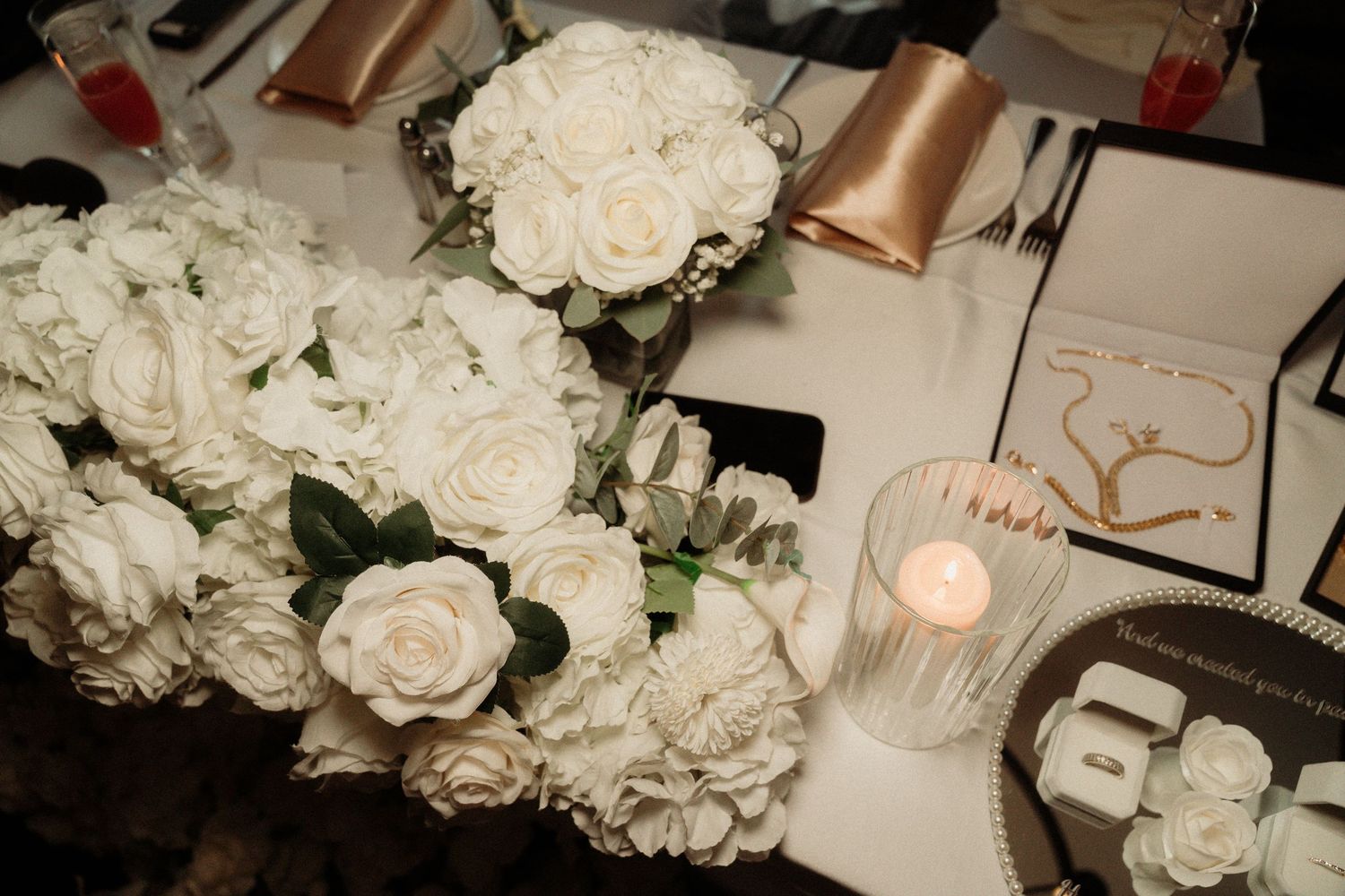 White rose floral arrangements and wedding decor details in soft lighting.
