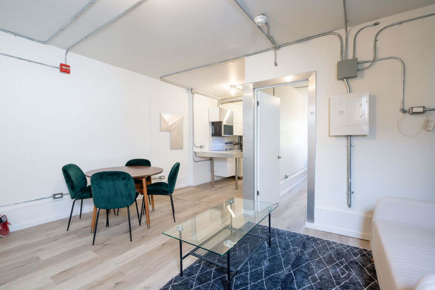 Clean white interior space with emerald green dining chairs and minimalist decor.