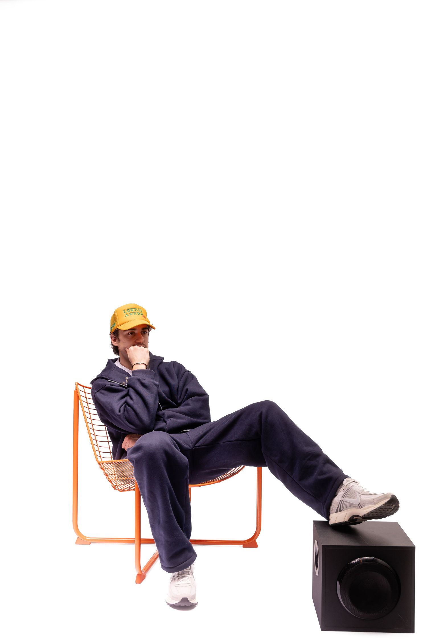 Figure in navy clothing sitting on orange chairs in various poses.