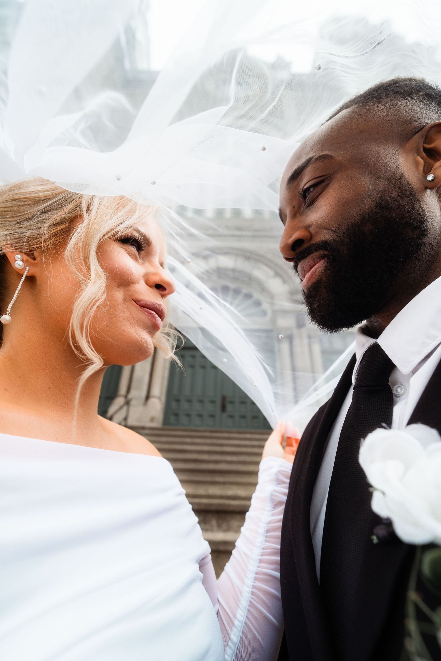 A romantic wedding moment captured in front of a historic church with flowing veil and classic architecture.