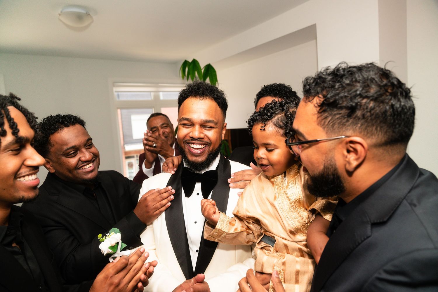 A joyful group shares laughter and smiles at a formal event wearing black and white attire.