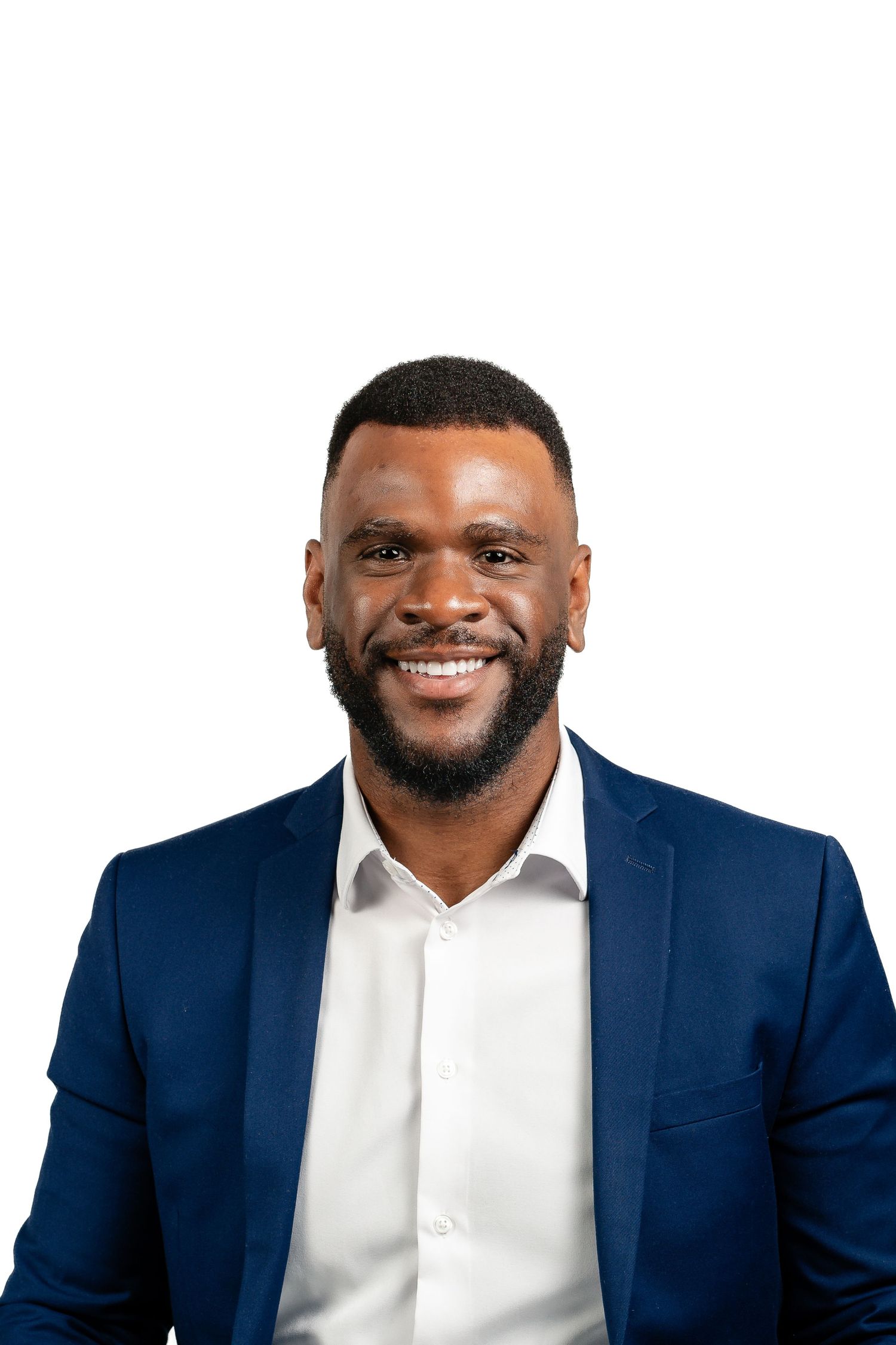 Confident businessman in a navy blazer and white shirt smiling warmly against white background.
