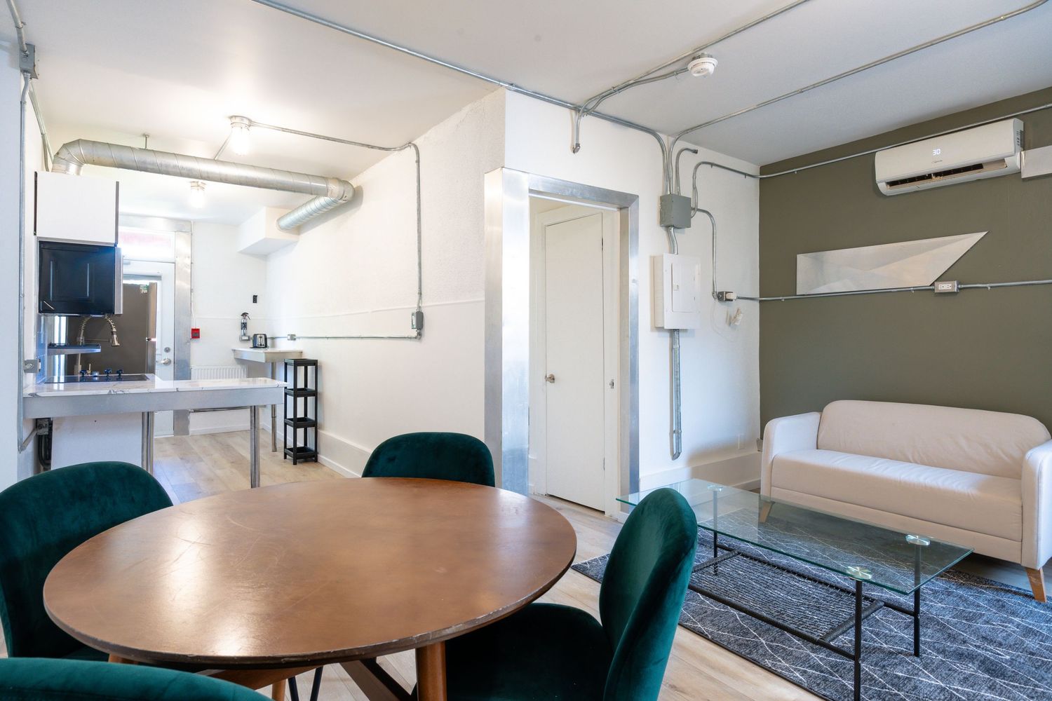 Modern office conference room with round wooden table and teal chairs in bright minimalist setting.