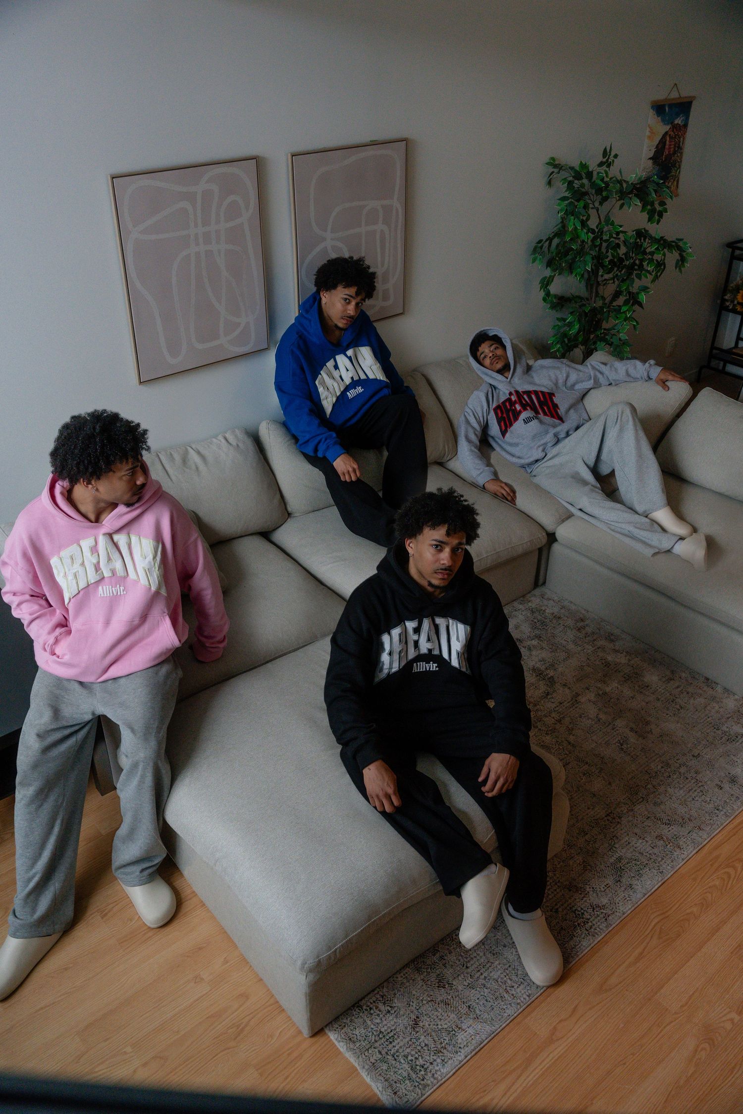 People lounging on a gray sectional sofa in casual streetwear.