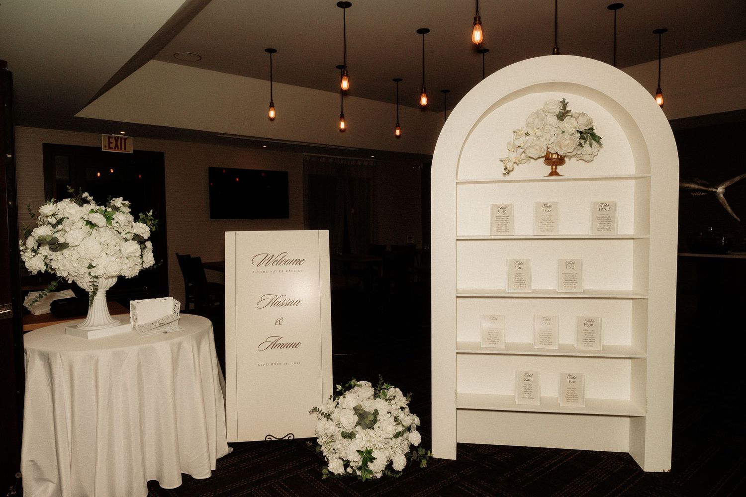 Panoramic view of an elegant wedding reception setup with white decor and ambient lighting.