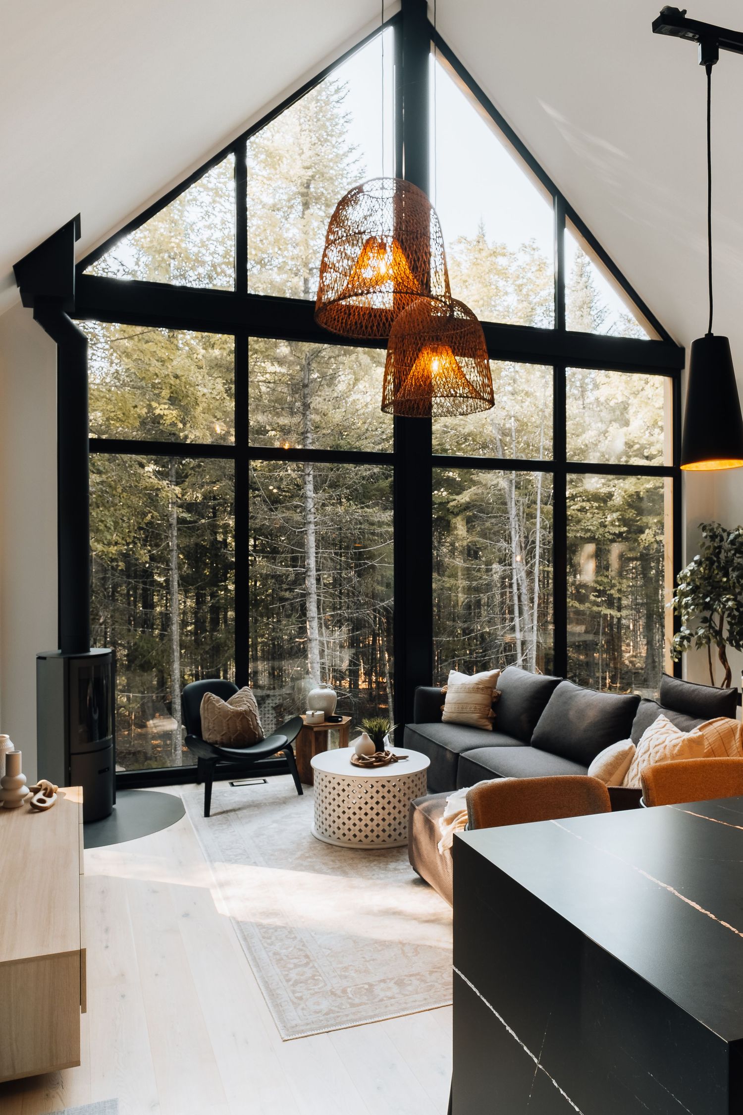 Contemporary A-frame living room with dramatic windows, modern furniture, and forest views.