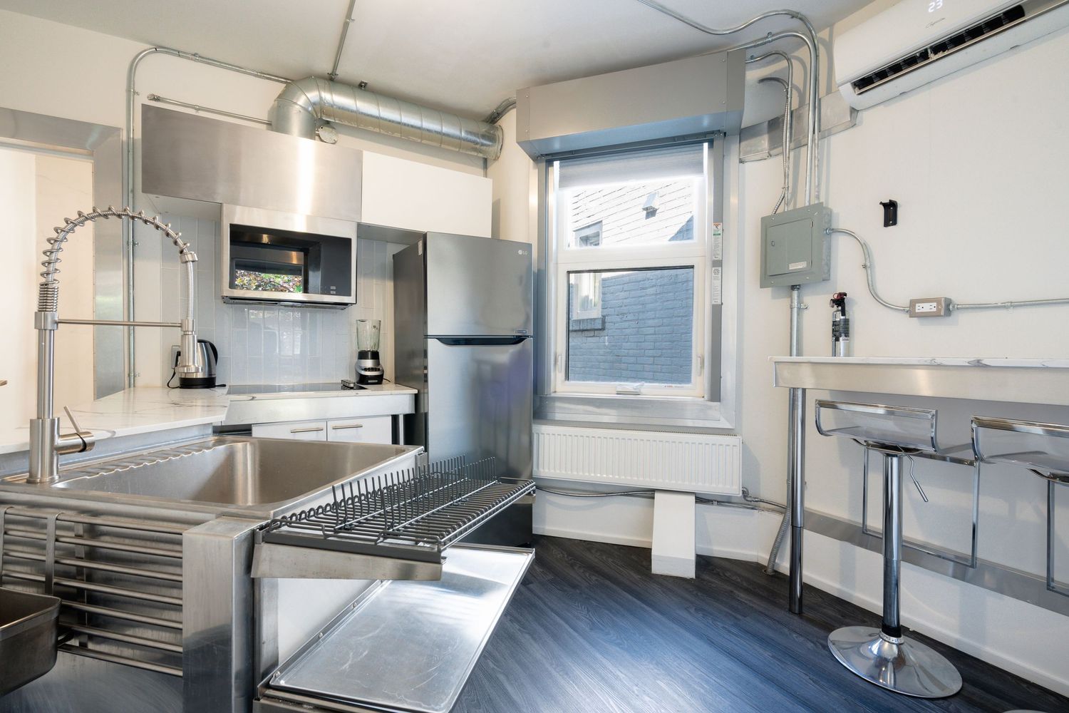 Industrial style kitchen with stainless steel appliances and white cabinets.