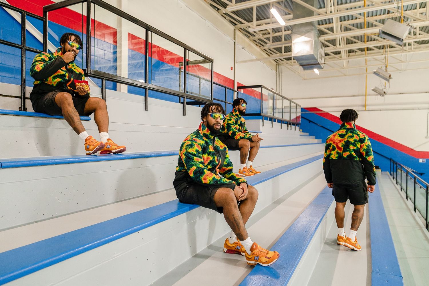People sitting along blue bleachers in indoor sports facility.