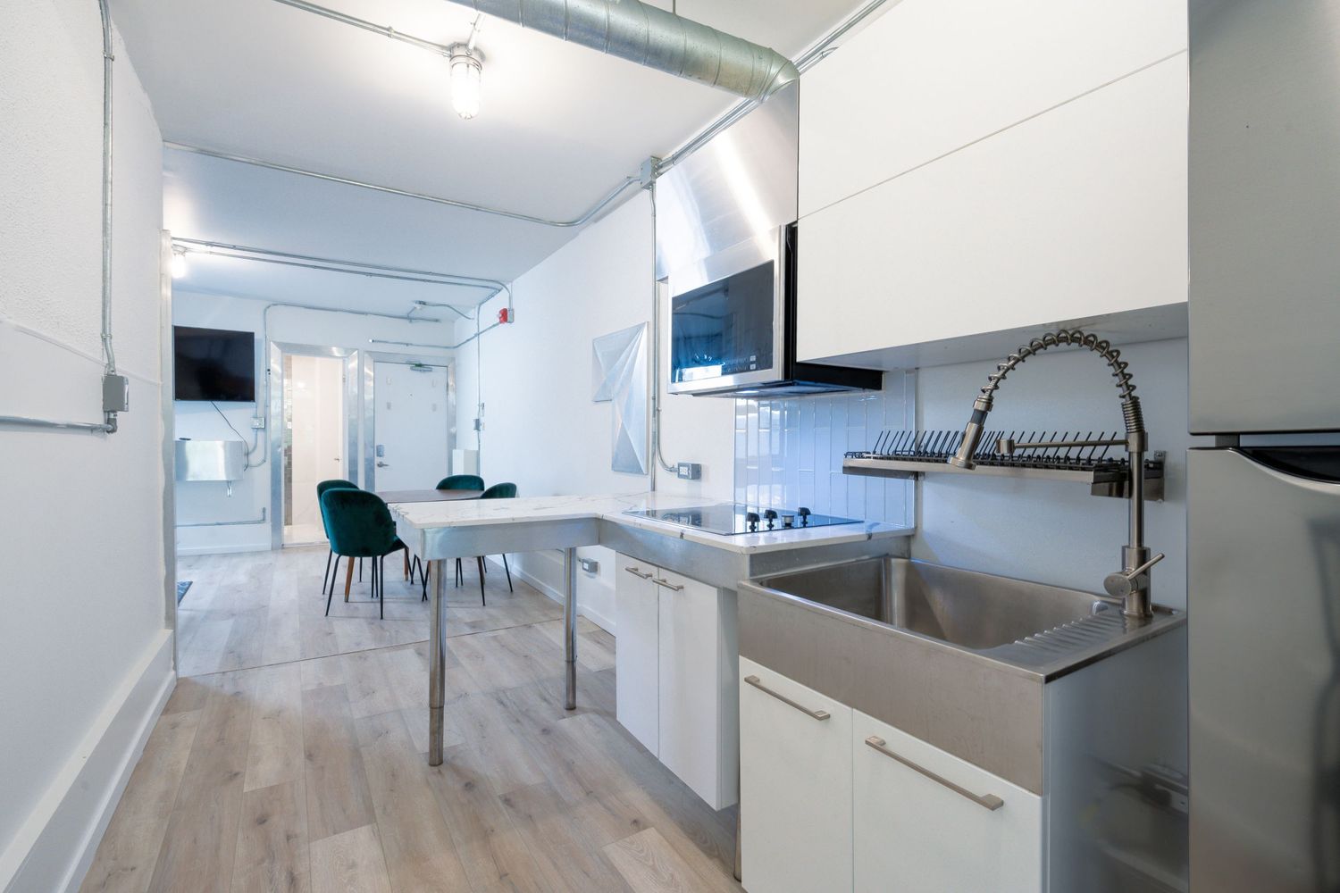 Bright white kitchen interior with sleek cabinetry and stainless steel appliances in a long galley layout.