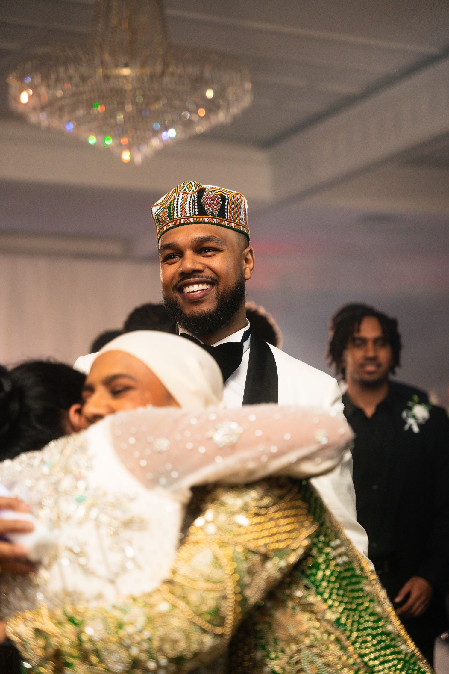 A joyous celebration at a wedding reception shows dancing under a crystal chandelier.