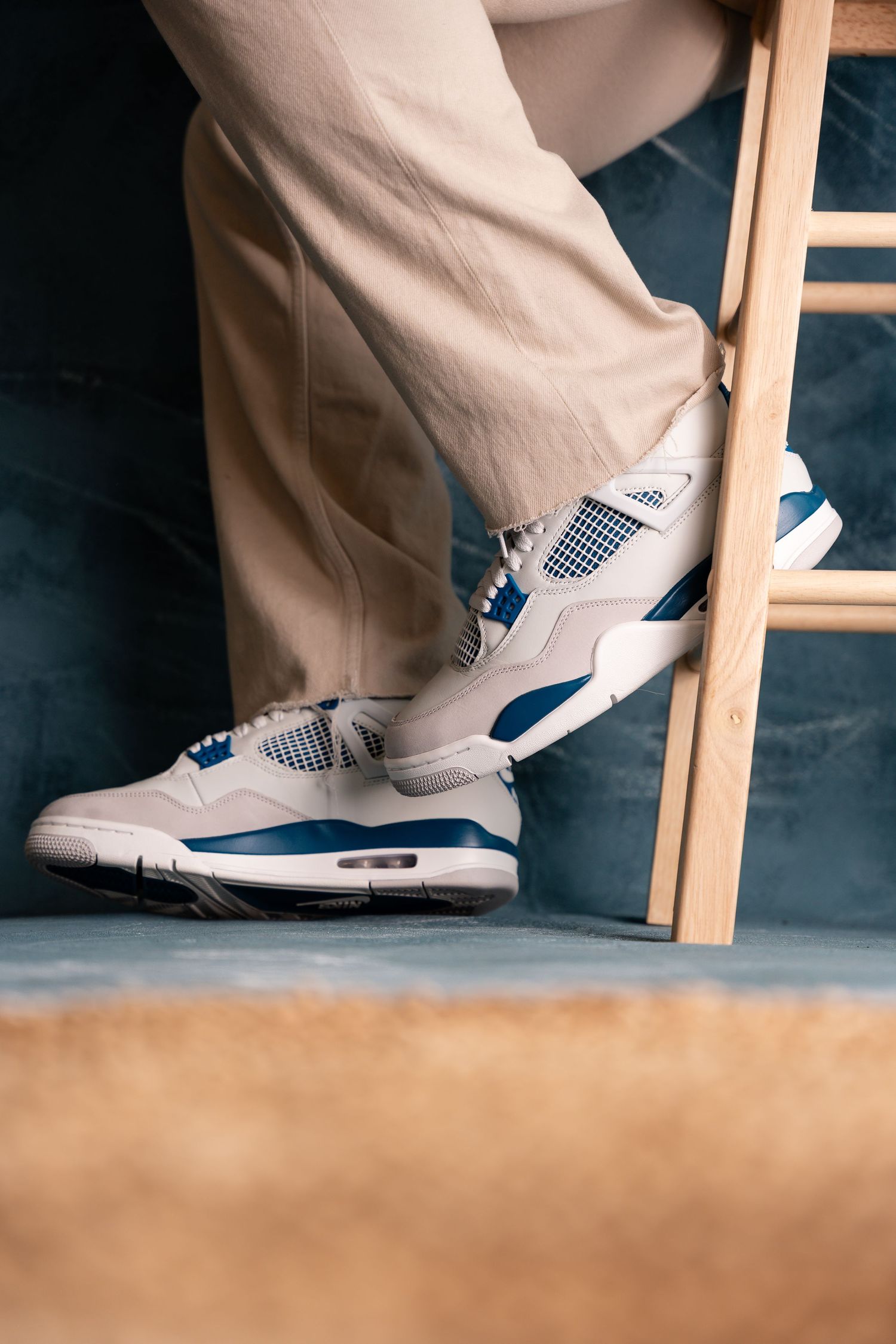 White and blue sneakers photographed on wooden steps in dramatic lighting.