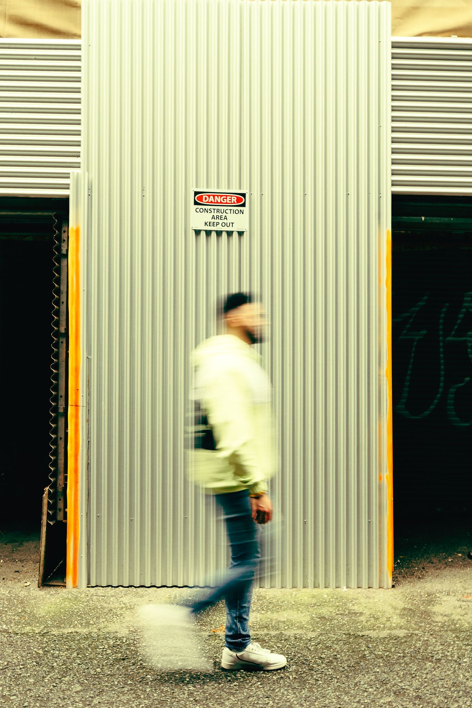 Motion blur of person walking past industrial metal storage units.