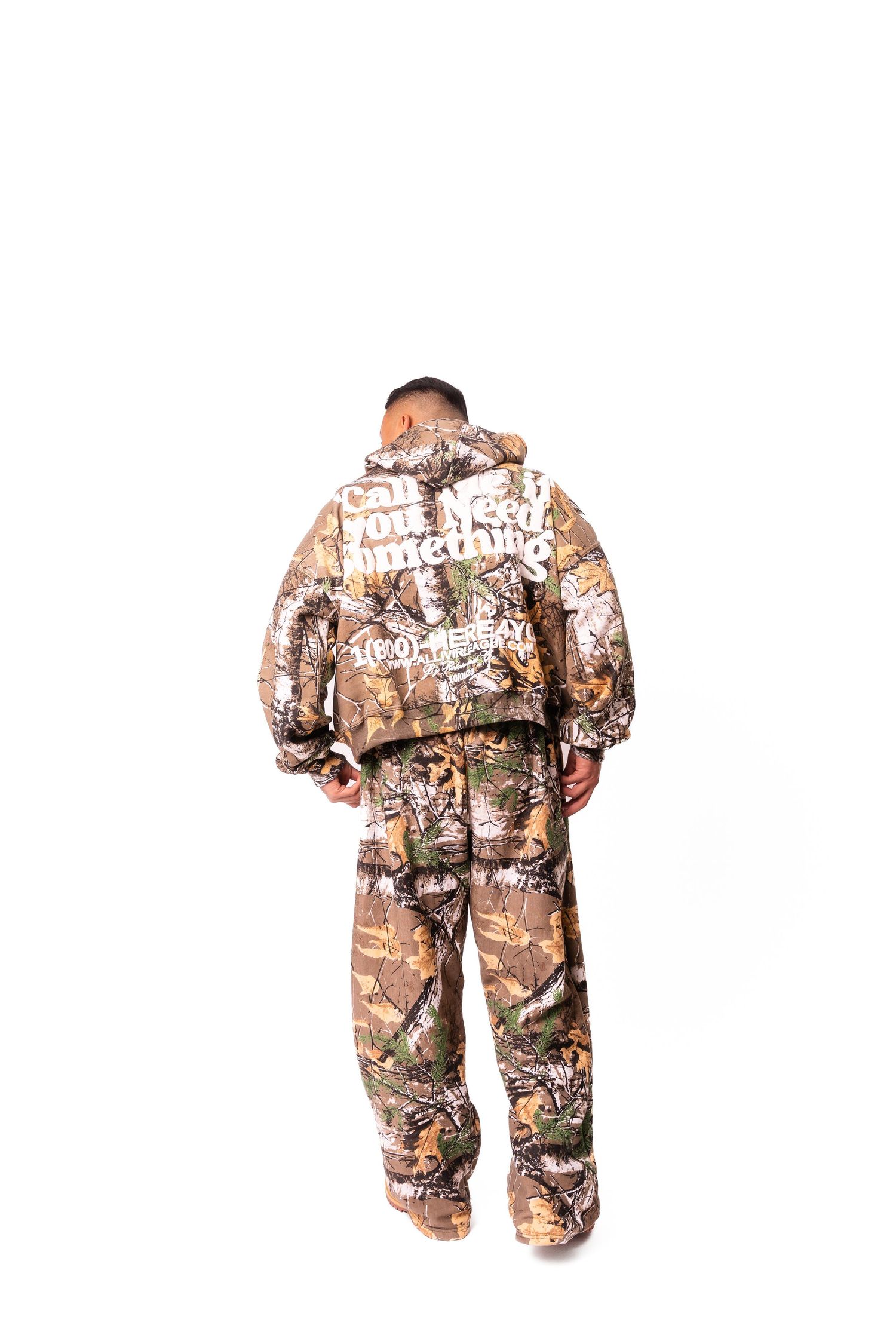 Back view of person wearing camouflage print sweatsuit against white background.