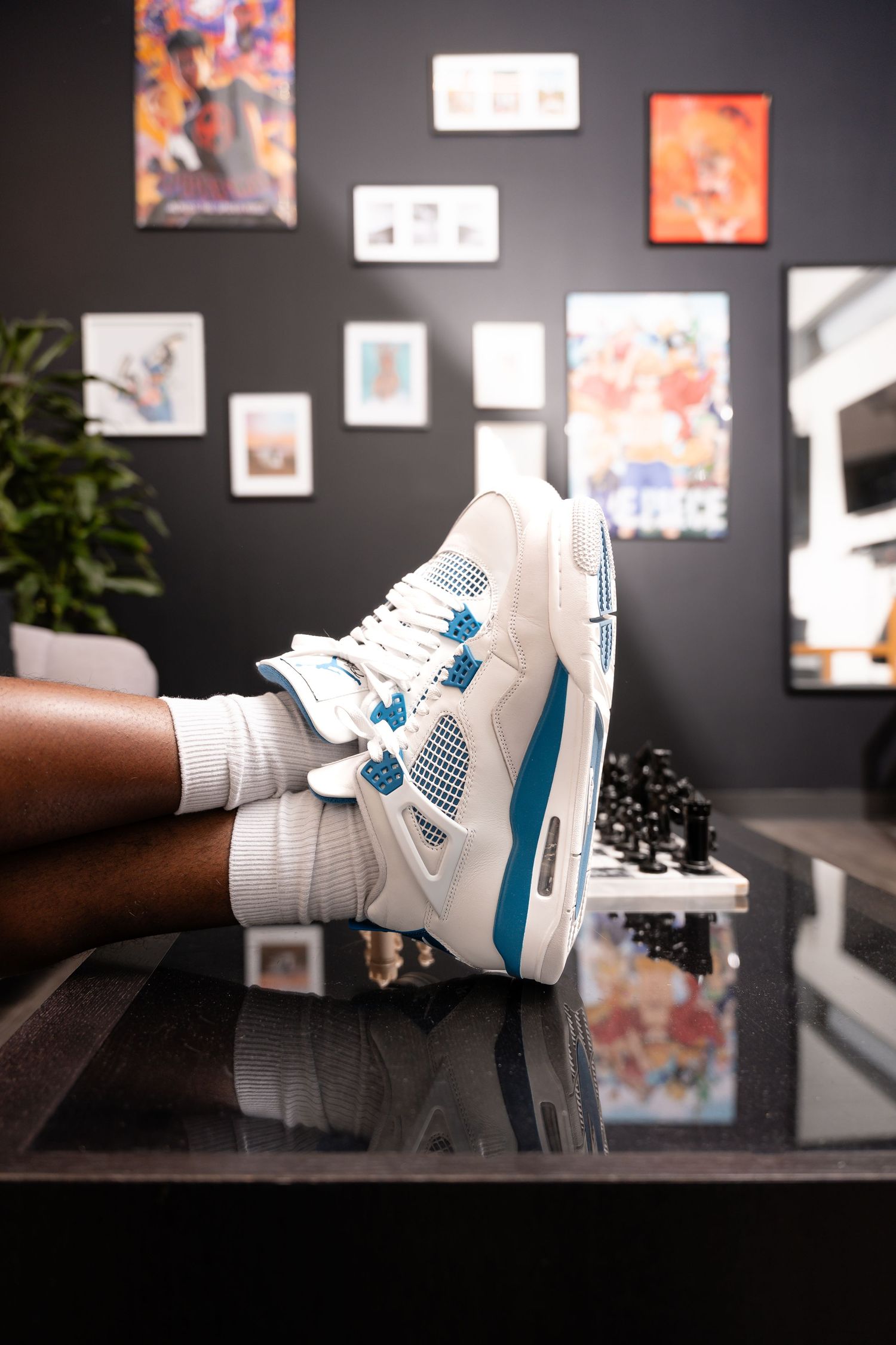 White and blue sneakers displayed against a dark wall with framed artwork.