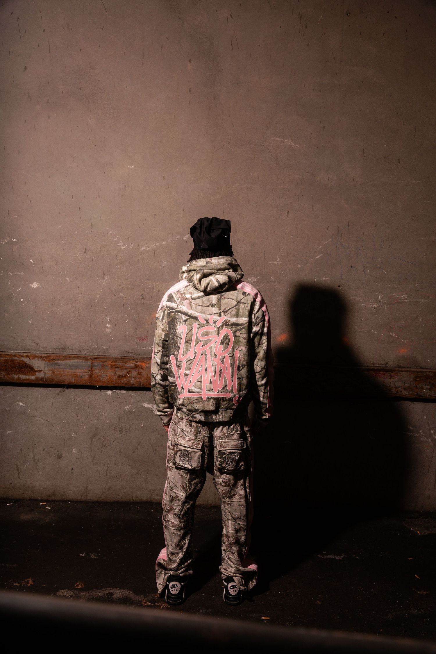 Camouflage outfit with pink details photographed against dark wall.