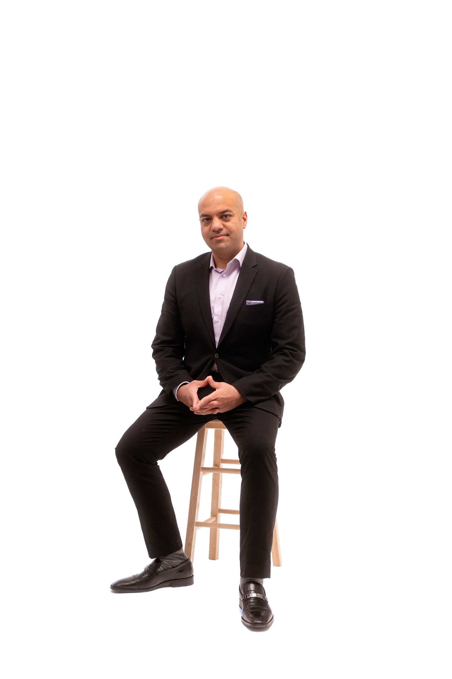 Professional portrait series showing person in suit seated on wooden stool against white background.