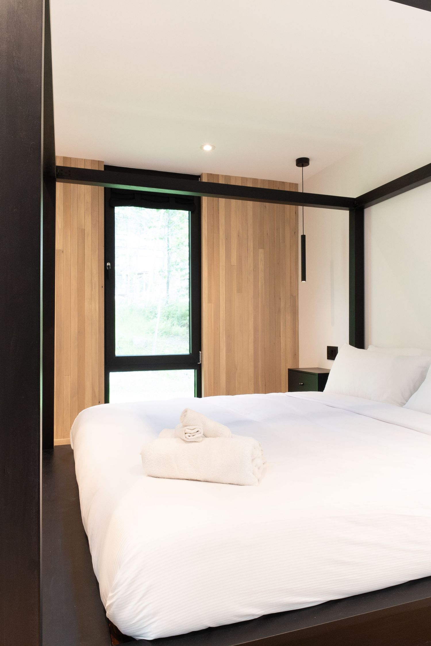 Contemporary bedroom with white walls, wooden accents, and minimalist black trim details.