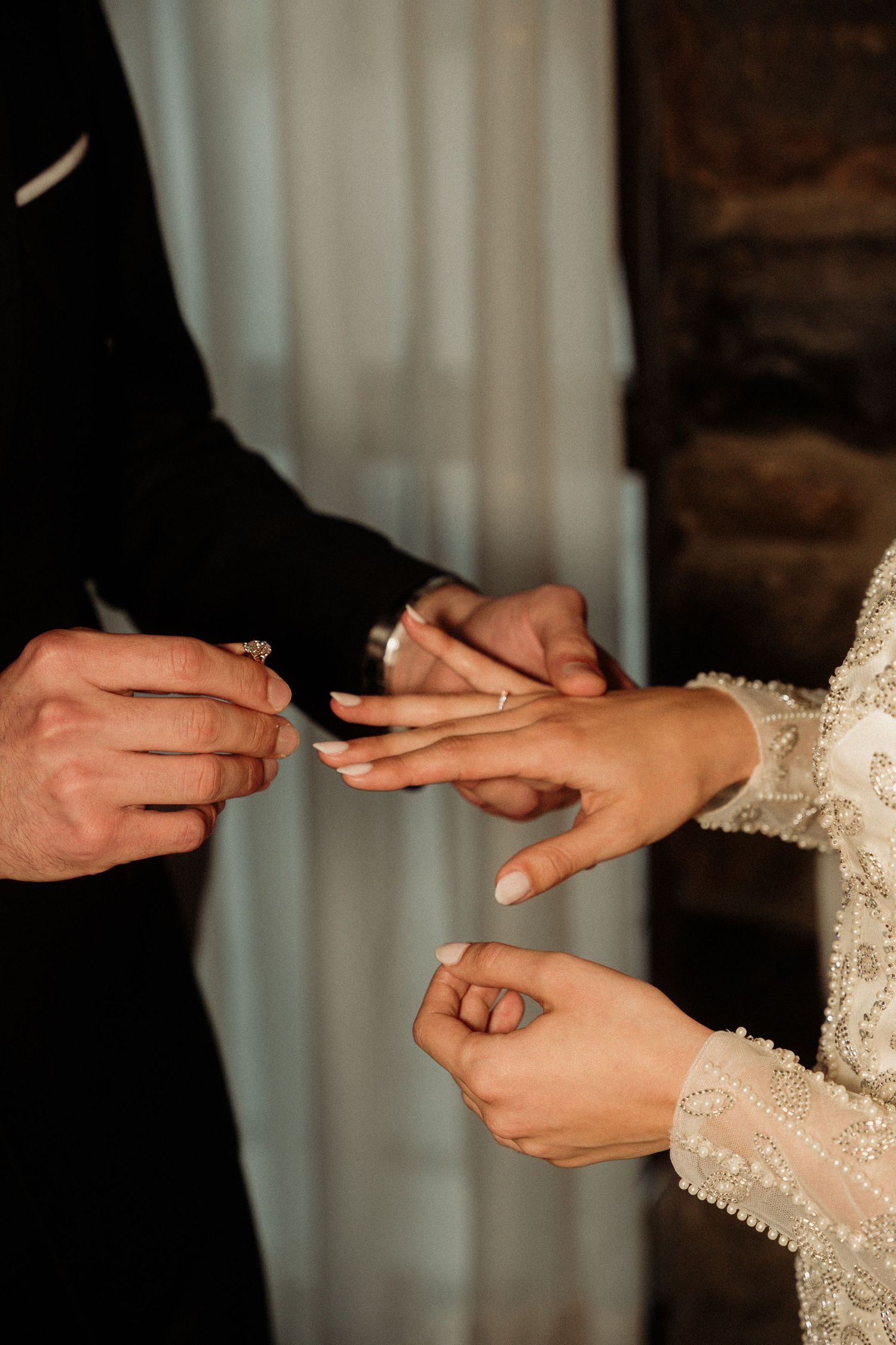 Series of intimate shots showing hands placing wedding rings on fingers against lace dress detail.