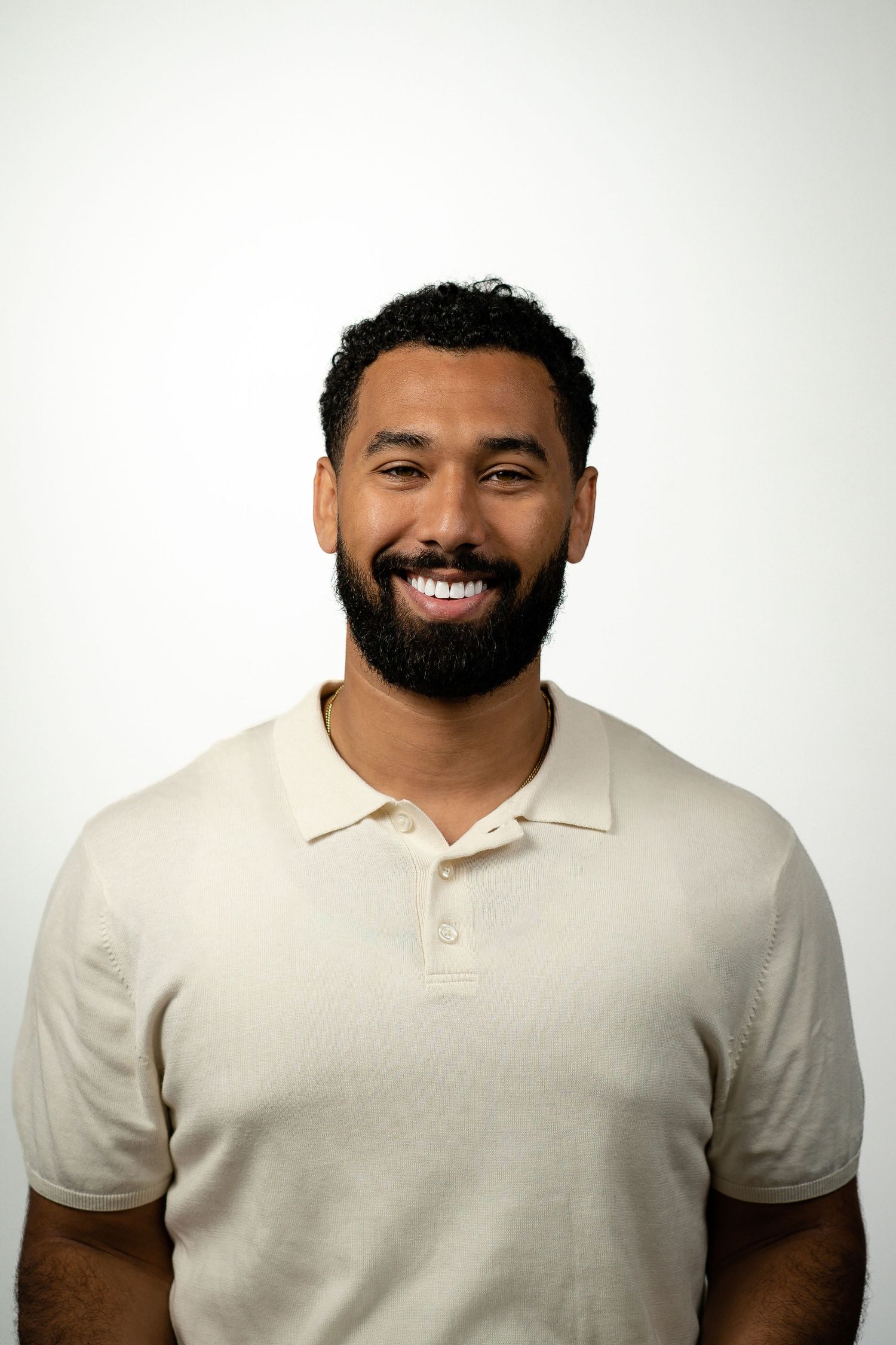 Cheerful man in cream polo shirt with beard against white background.