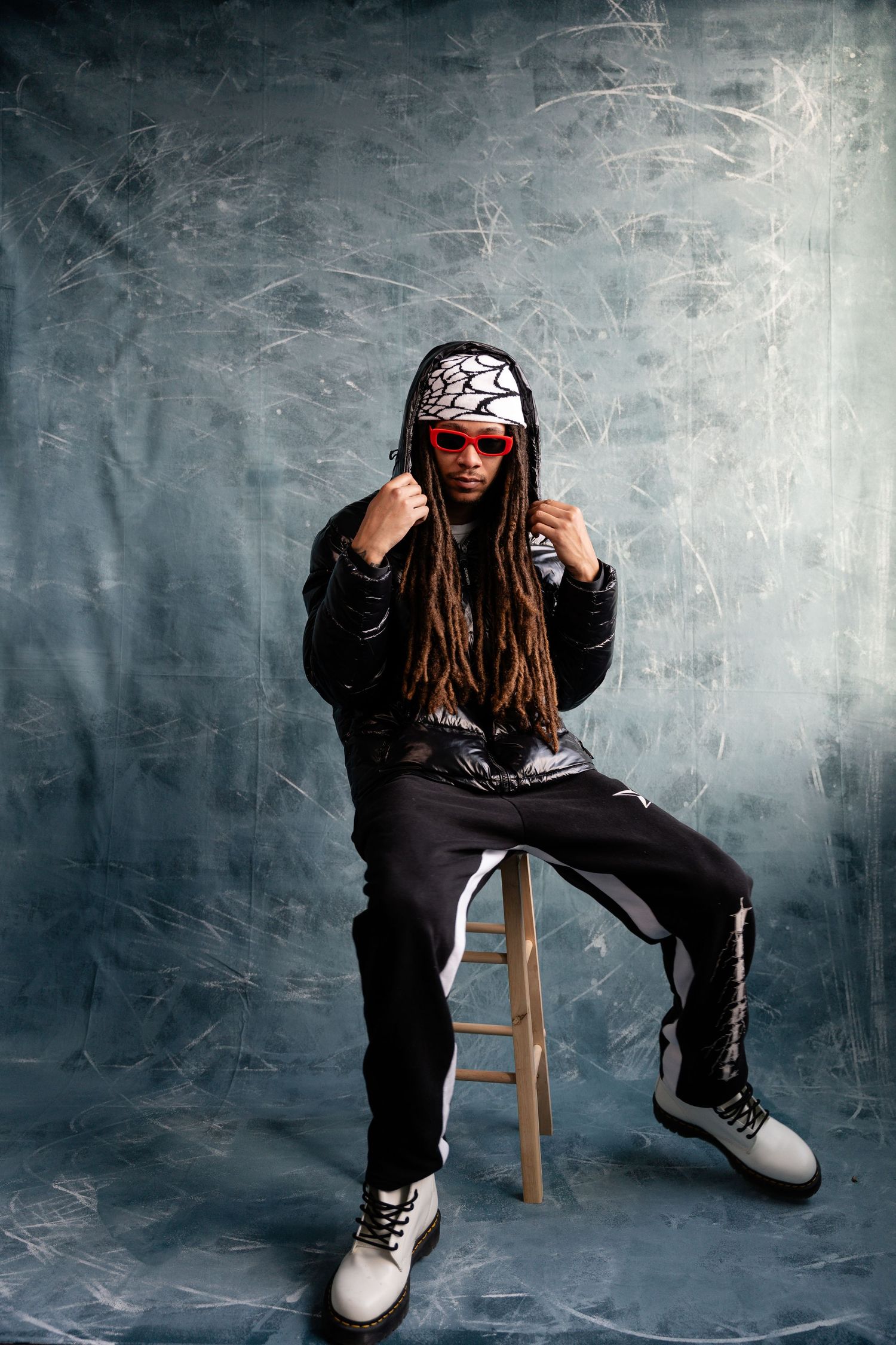 Urban style photoshoot against textured gray wall with wooden stool.
