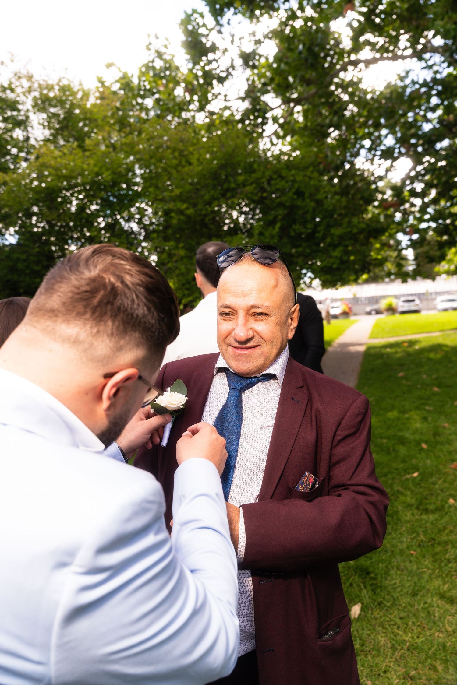 Wedding party members sharing emotional moments outdoors on a sunny day.