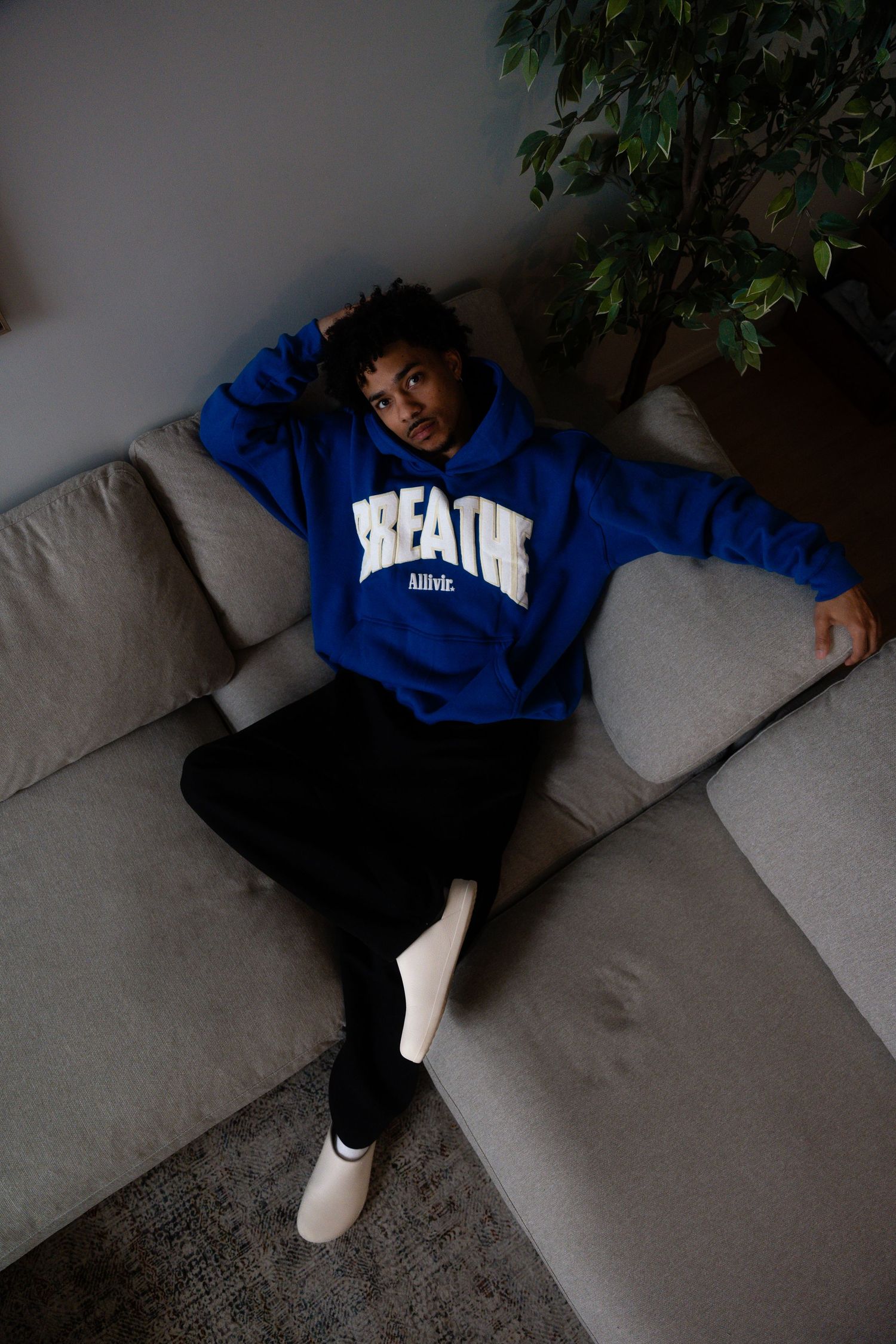 Person in blue hoodie relaxing on gray sectional sofa.