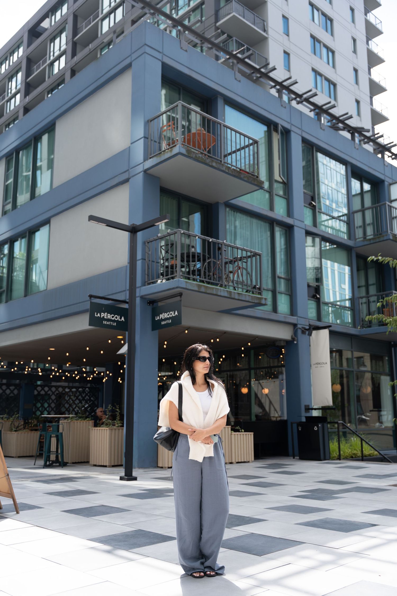 Modern glass apartment building exterior with retail space and geometric patterns.
