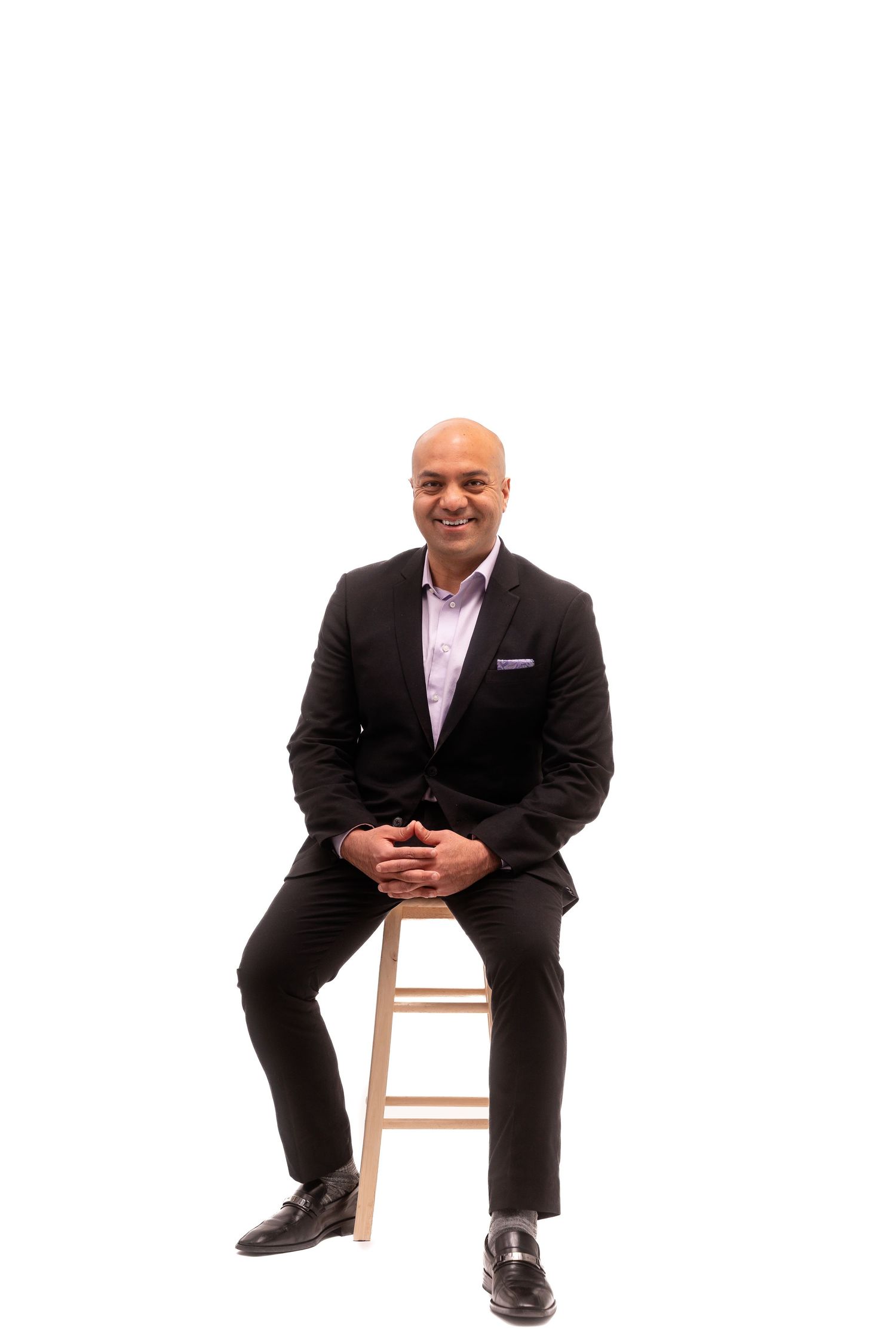 Person in business attire shown in various seated poses on wooden stool.