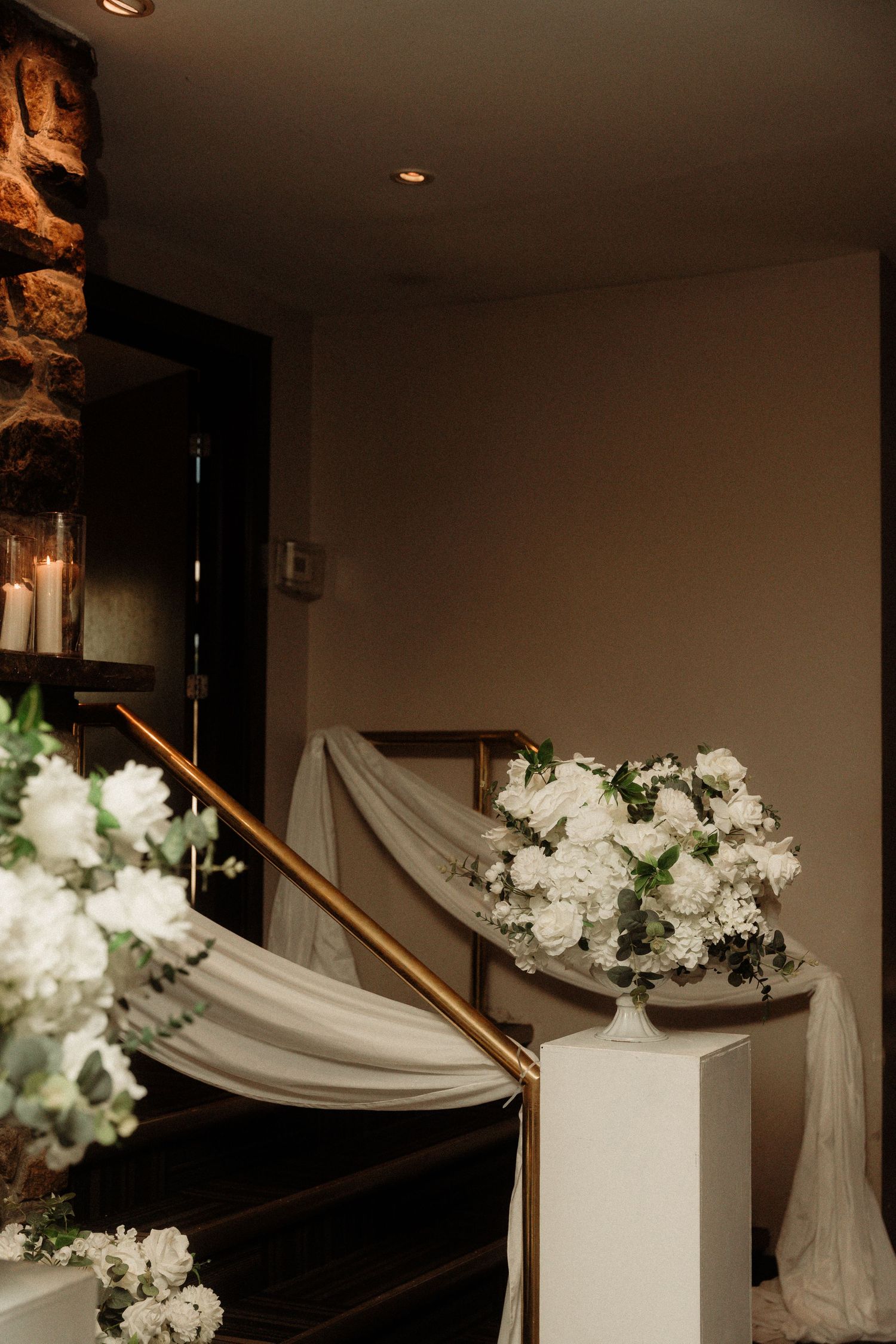Wedding staircase decorated with white floral arrangements and flowing fabric draping.