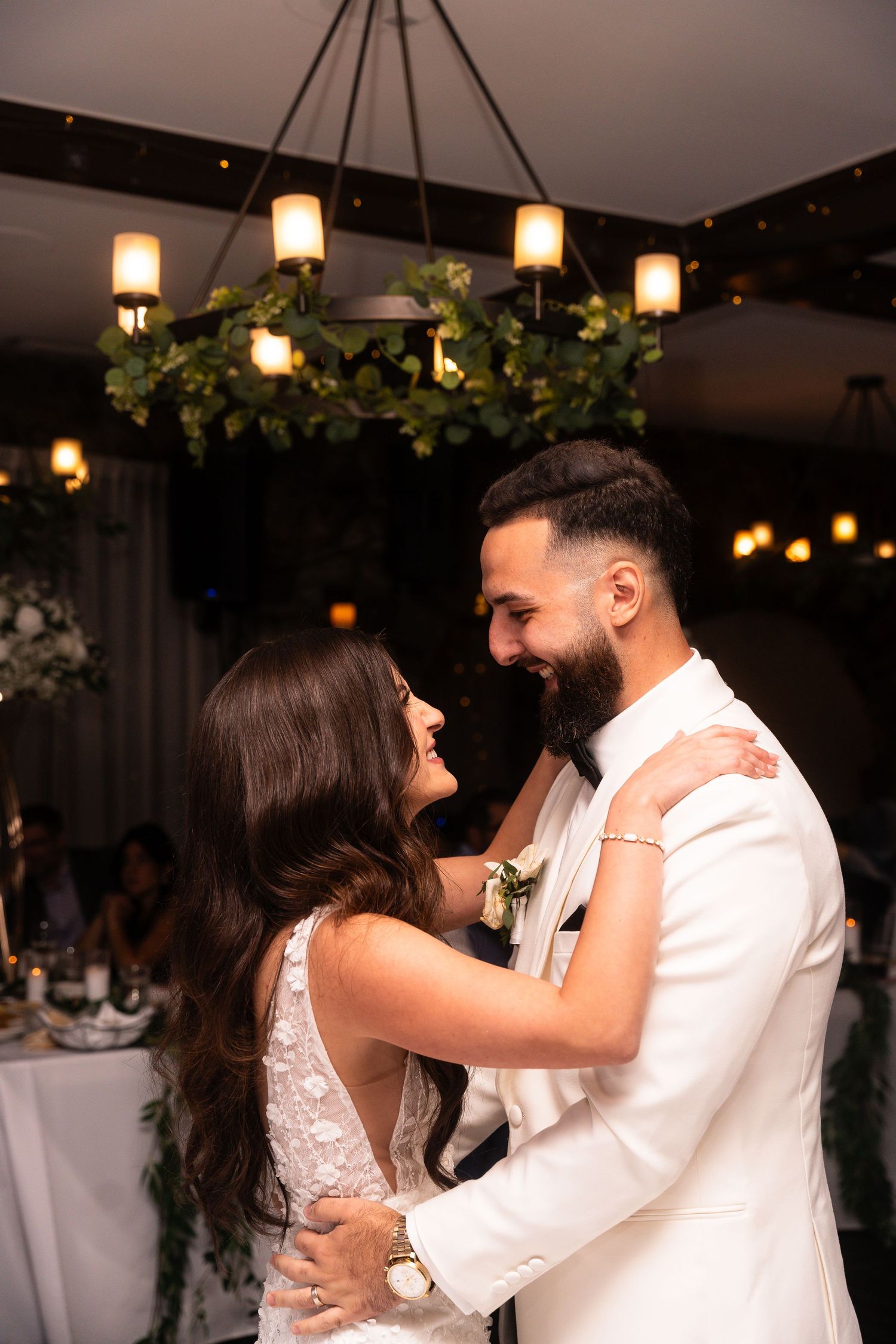 Couples dancing together at an indoor wedding reception with warm lighting and hanging lanterns.