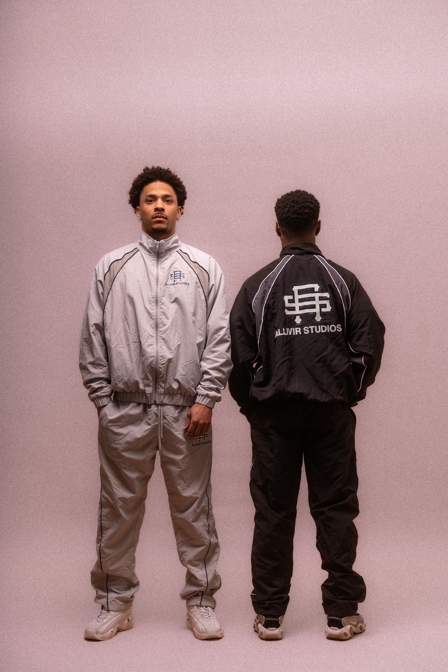 Four people wearing contrasting black and white tracksuits standing together.