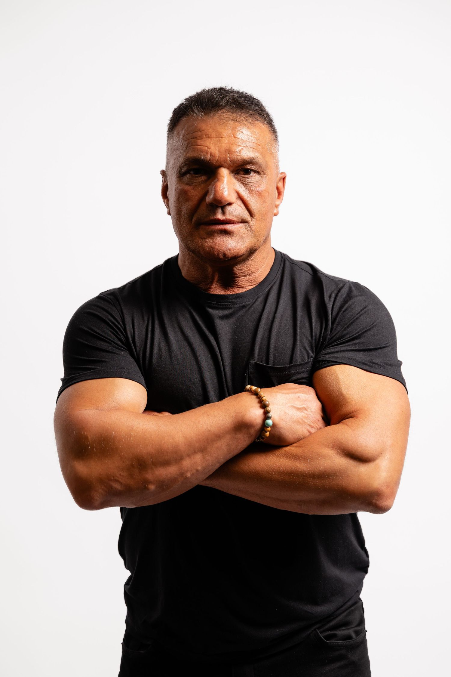 Athletic person in black t-shirt posing with crossed arms against white background.