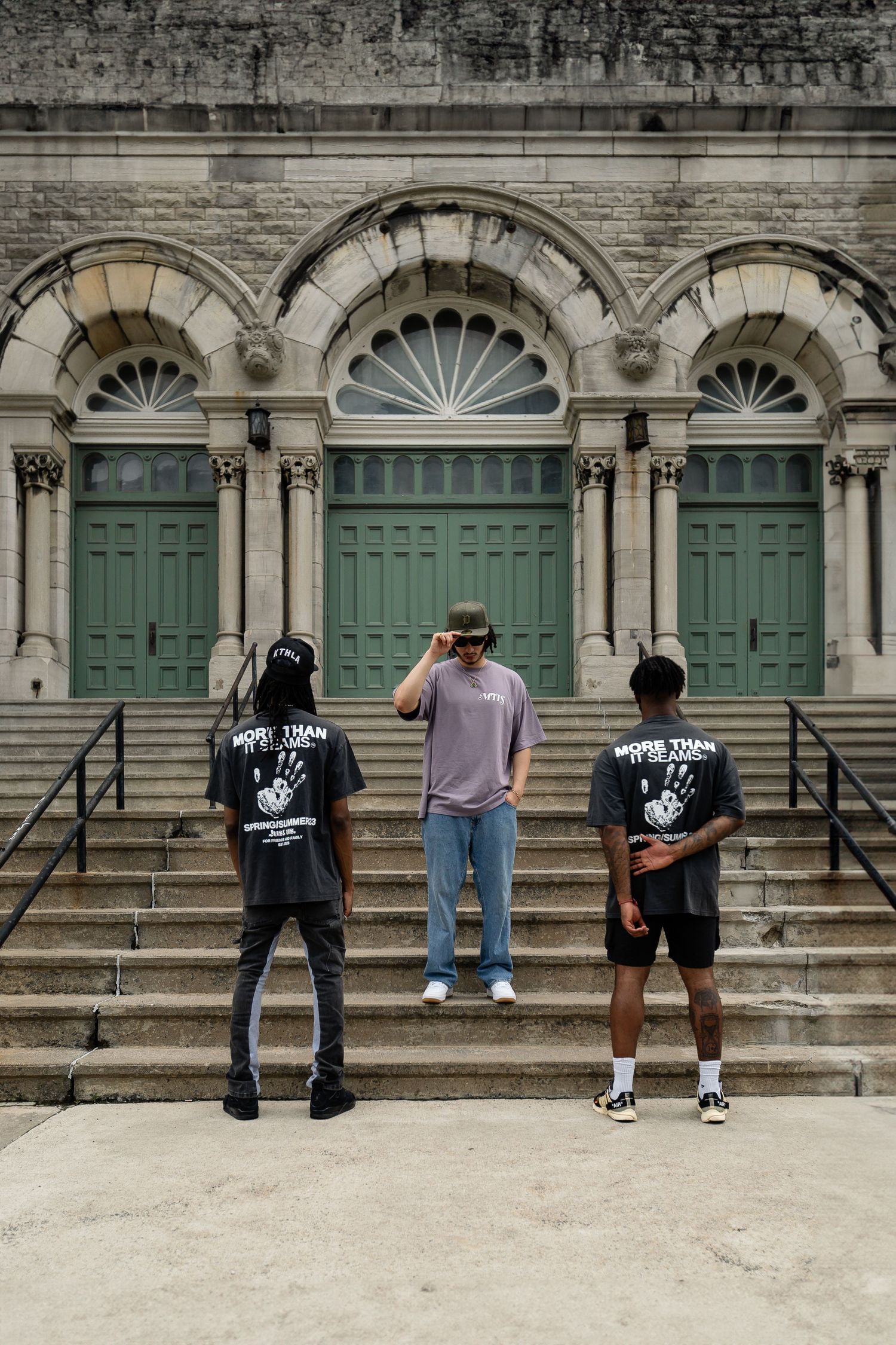 People sitting on stone steps in front of green doors of historic building.