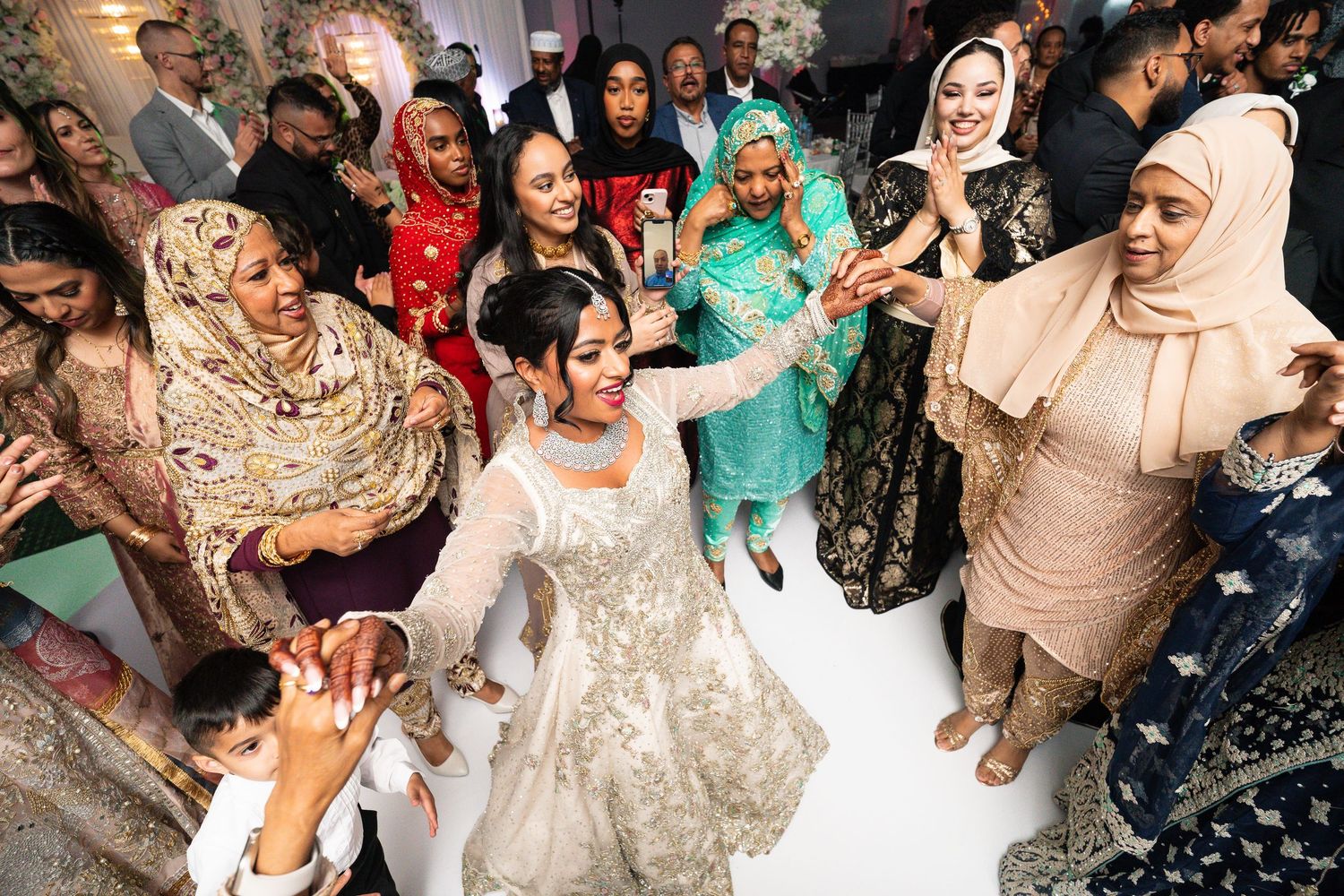 People dancing and celebrating at a lively wedding reception with colorful traditional outfits and decor.