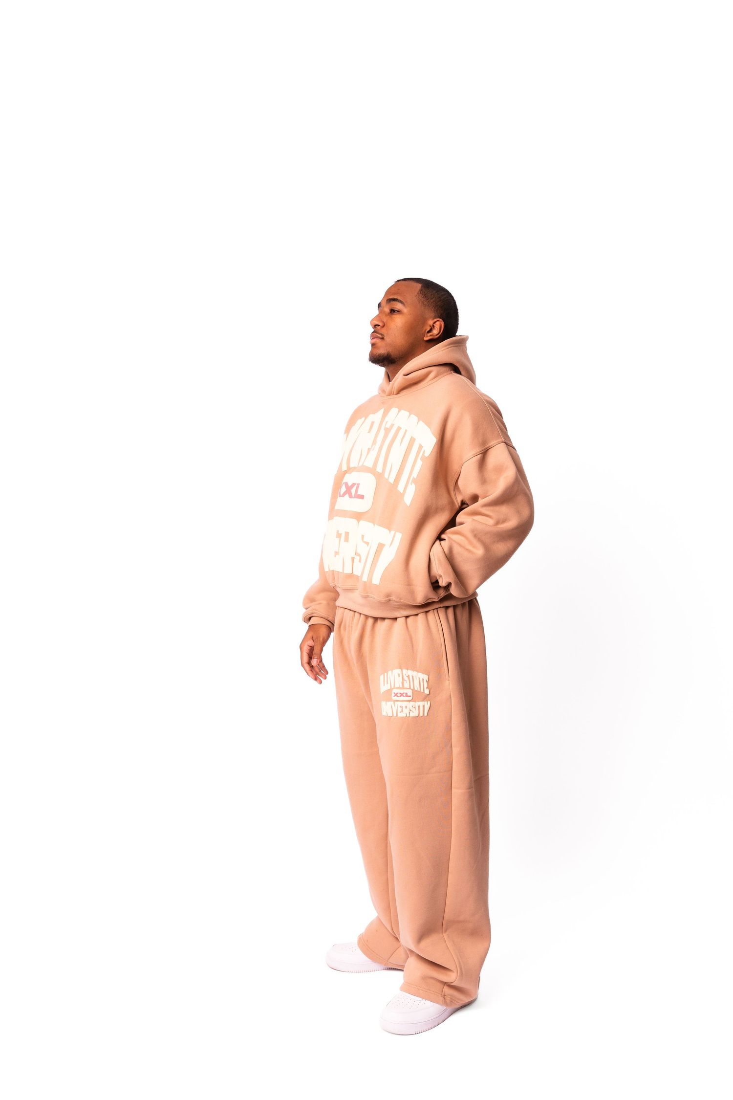 Person wearing peach-colored sweatsuit standing against white background.
