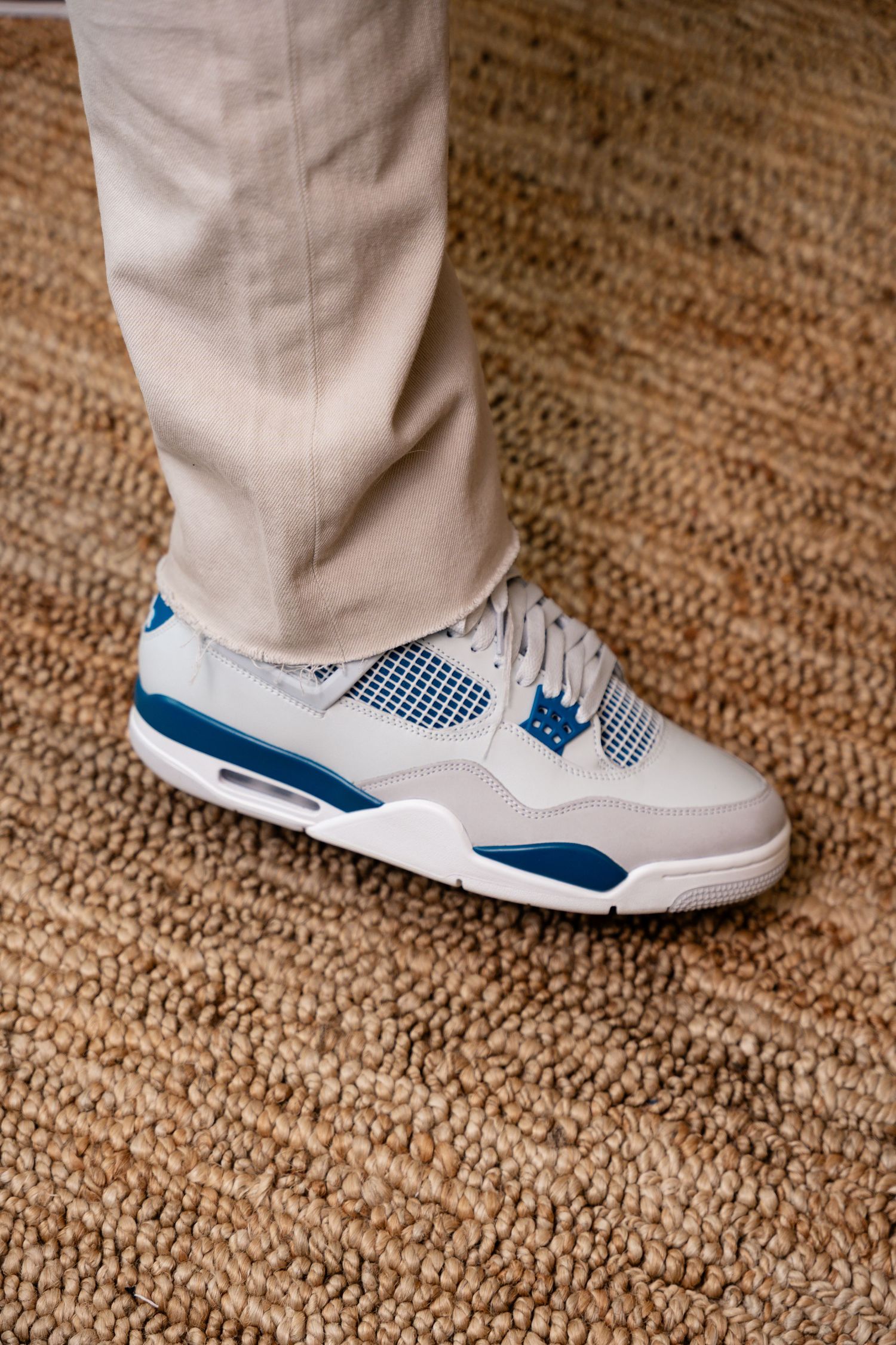 White and blue athletic sneakers shown on a beige carpet in detail.