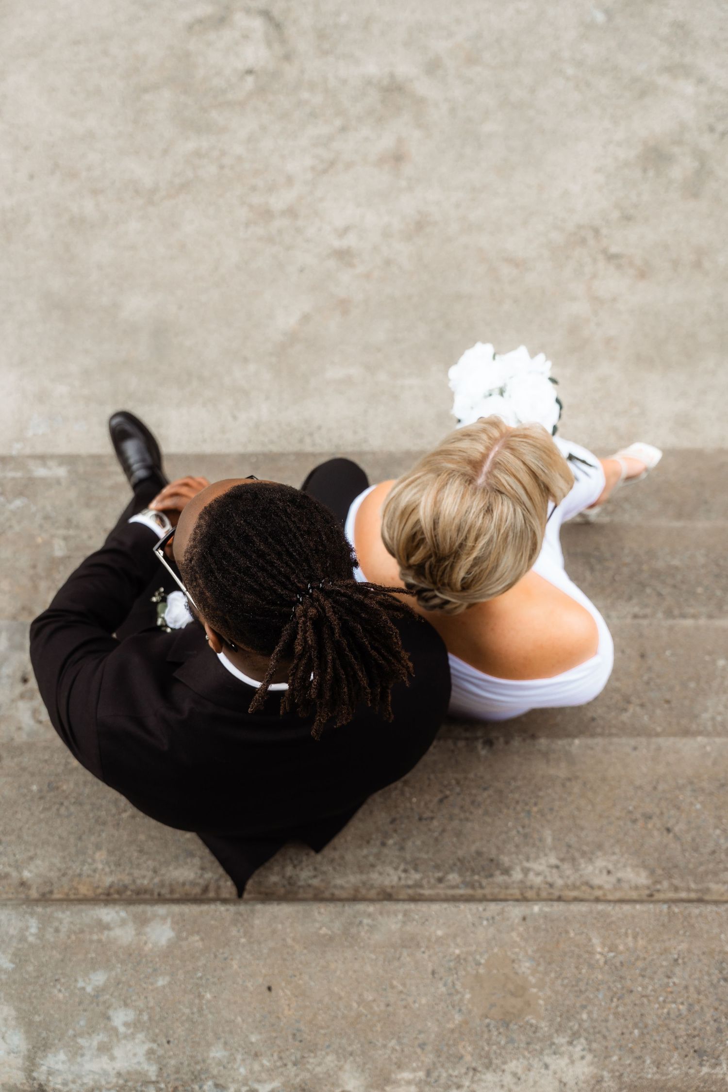 Artistic wedding photo sequence showing couple lying on concrete ground in formal attire.