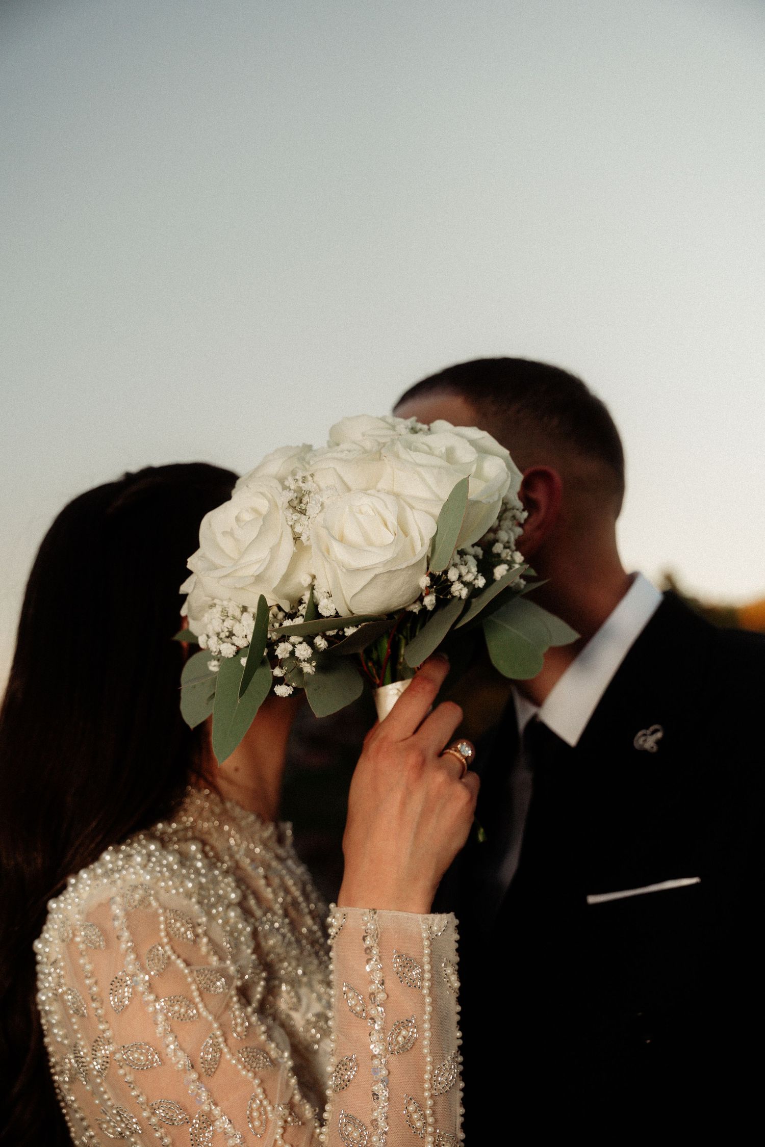 Intimate wedding moment captured during golden hour with white floral crown.