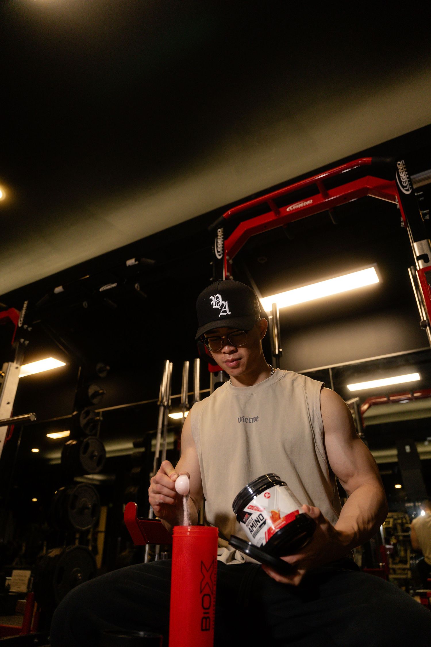 Person in white shirt hitting a red punching bag in dark gym setting.