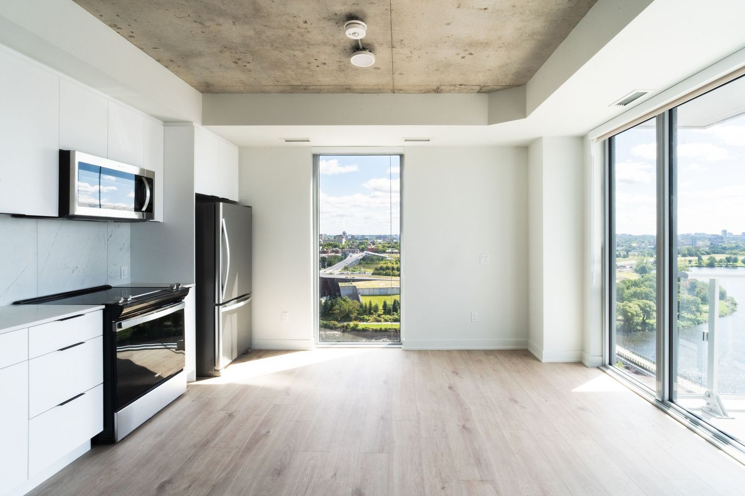 Wide angle view of empty modern apartment interior with white walls and concrete ceiling.