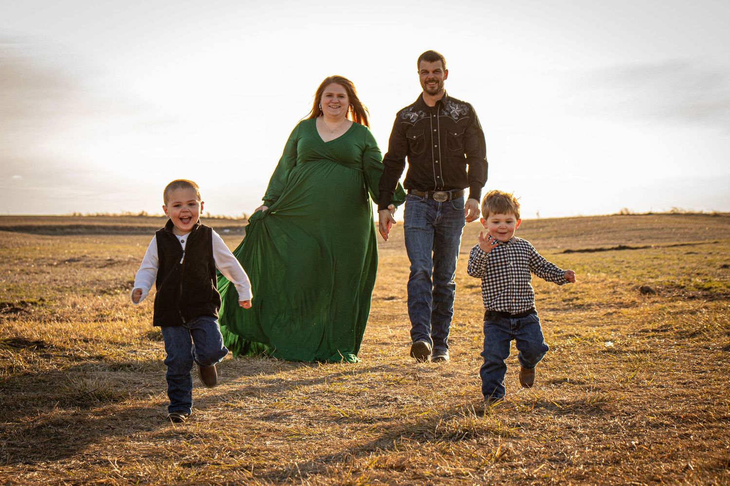 Expectant mom with family running in an Iowa field