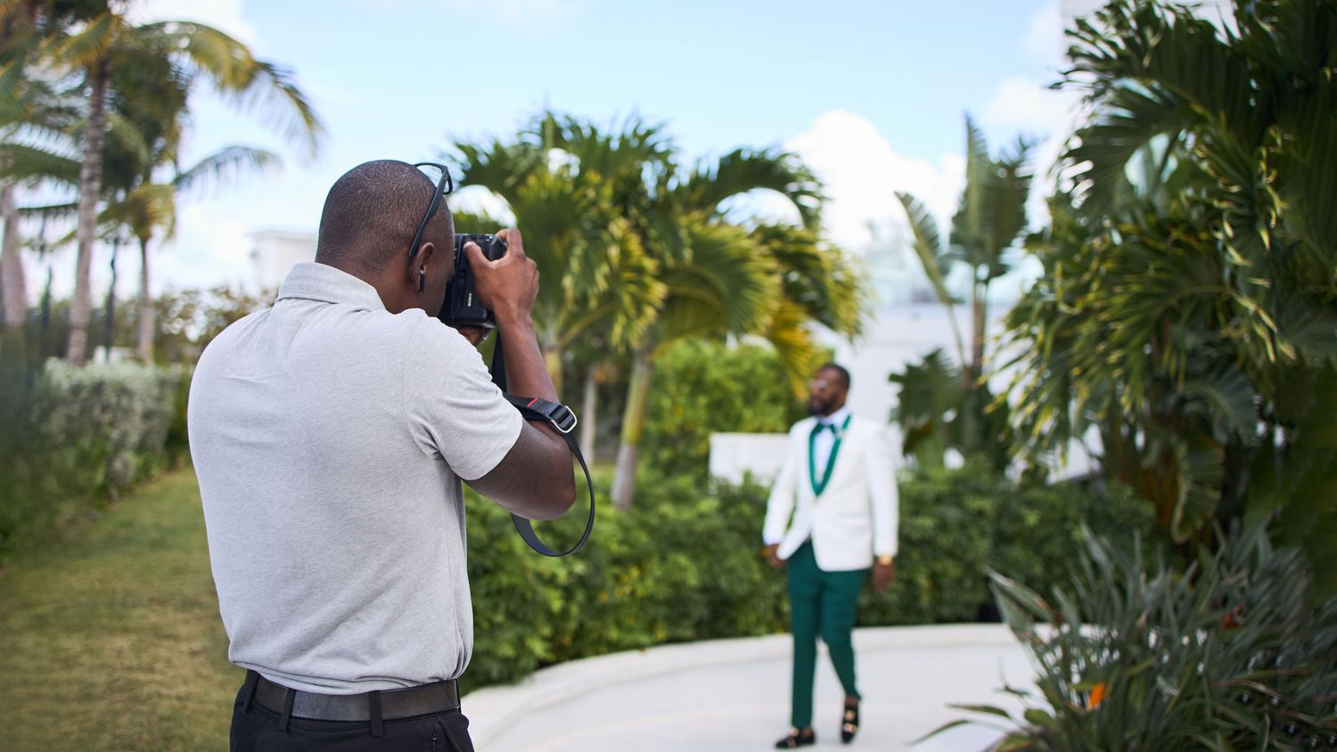 Palm trees and greenery line an outdoor walkway of a tropical wedding ceremony venue.