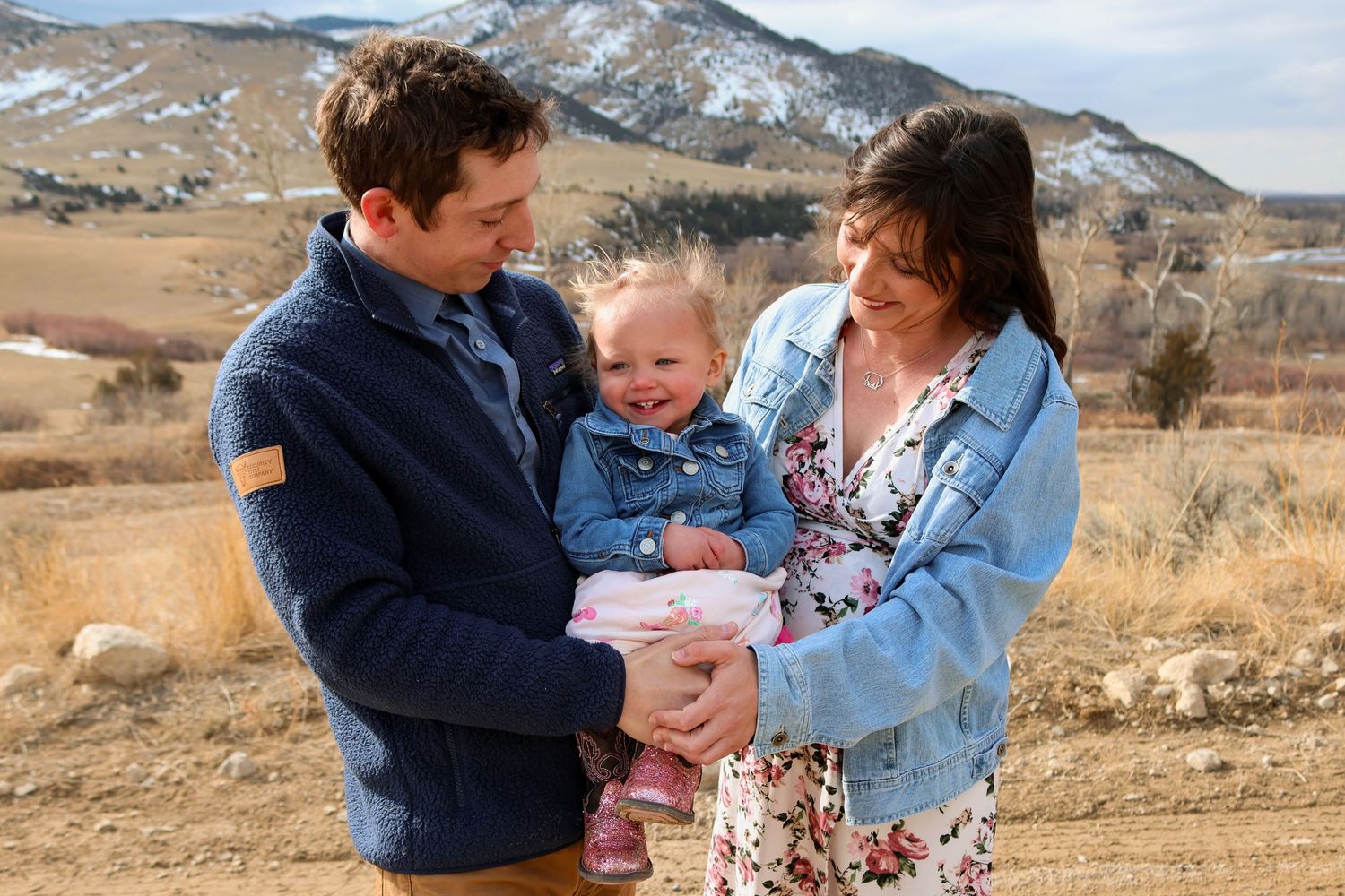 A family captures a candid moment together outdoors against a backdrop of rugged mountain scenery.