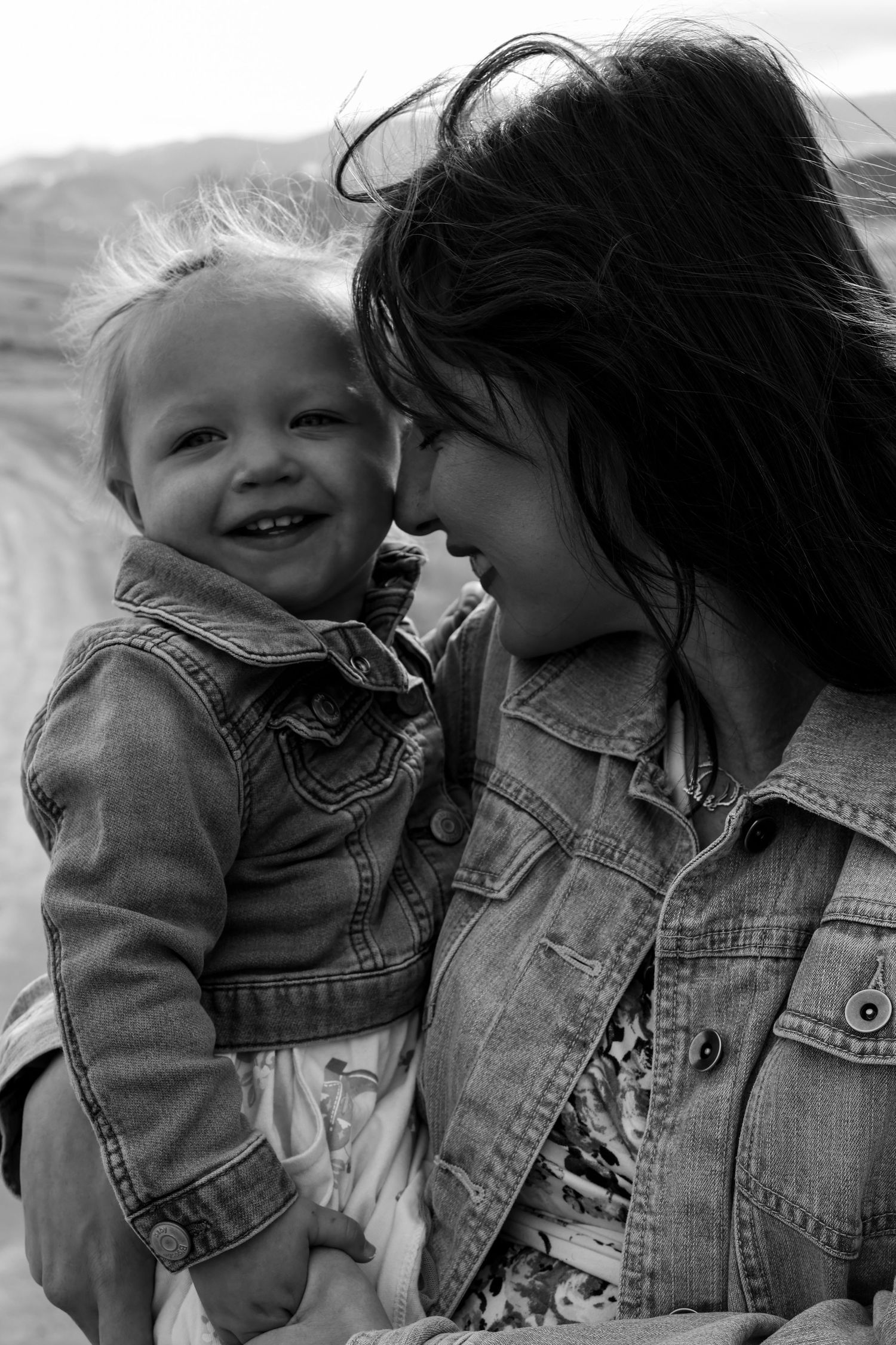 A touching black and white portrait of a joyful moment between parent and child wearing matching denim jackets.