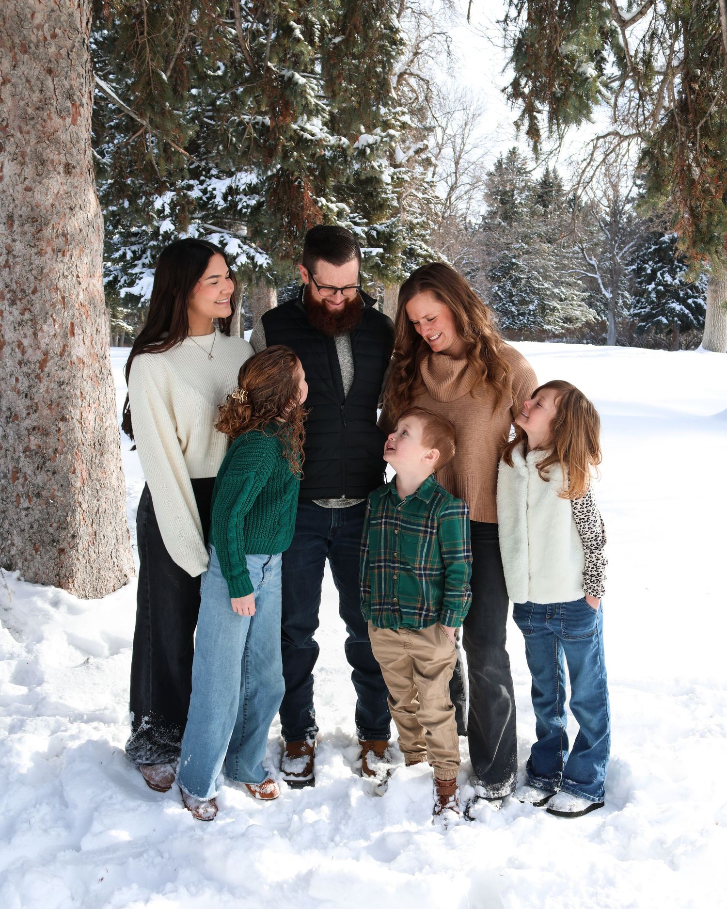 A group enjoys a winter photo moment together in a snow-covered forest setting among evergreen trees.