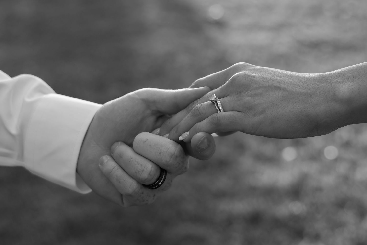 Wedding rings being exchanged between partners' hands in a series of black and white close-up shots.