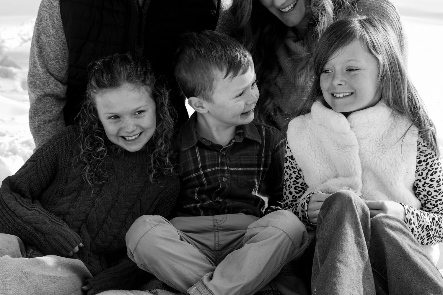 A collage strip of black and white photographs showing intimate family moments and hugs between loved ones.