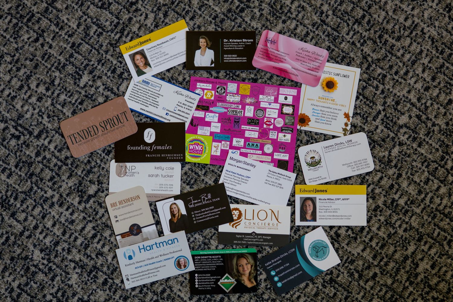 A collection of business cards and promotional materials scattered on a textured gray carpet background.